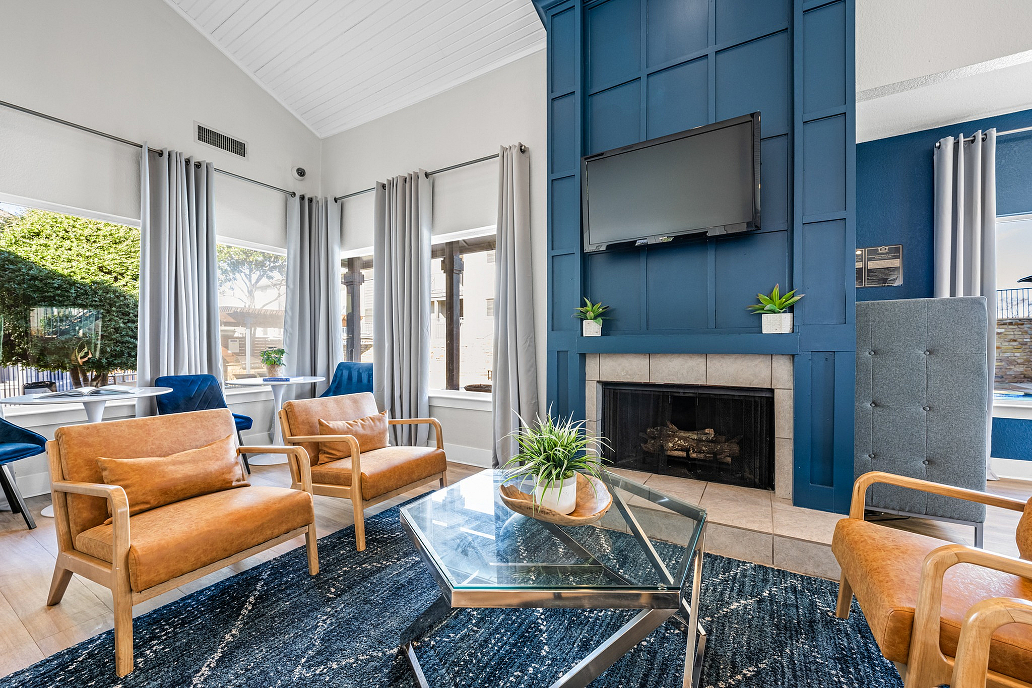 Inviting living room with elegant leather seating, a cozy fireplace, large windows with natural light, and modern decor.