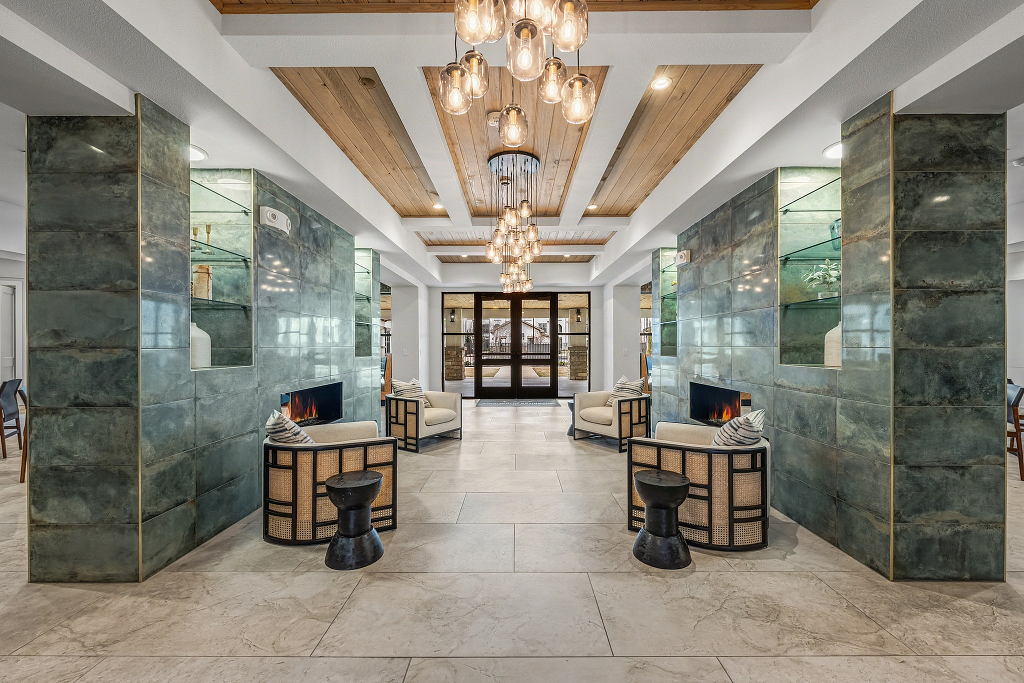 Elegant lounge area with plush seating, modern fireplaces, and artistic lighting in a luxurious apartment complex.