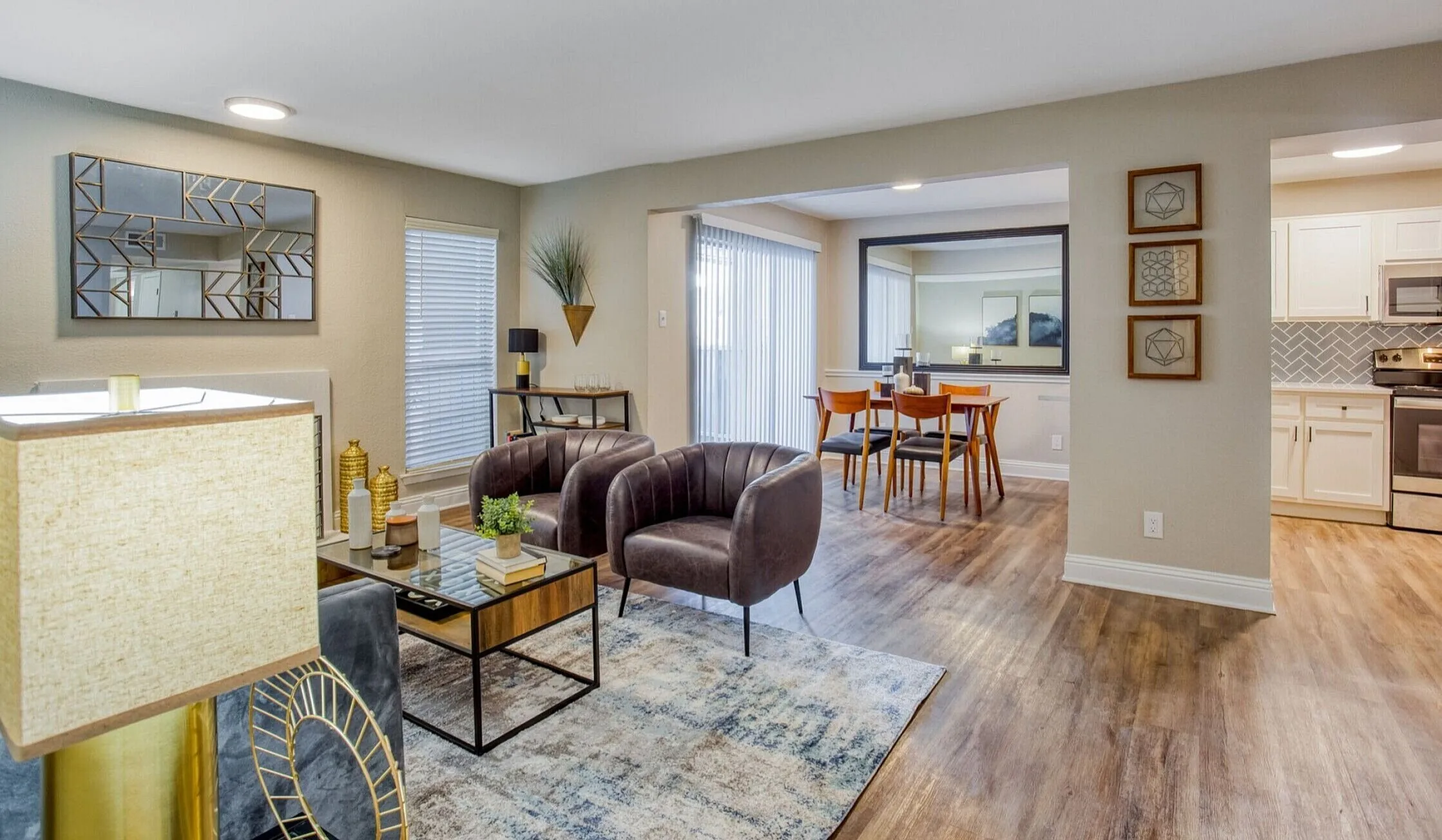 Modern open-plan living room with stylish furnishings, leading to a chic dining area and contemporary kitchen with stainless steel appliances.