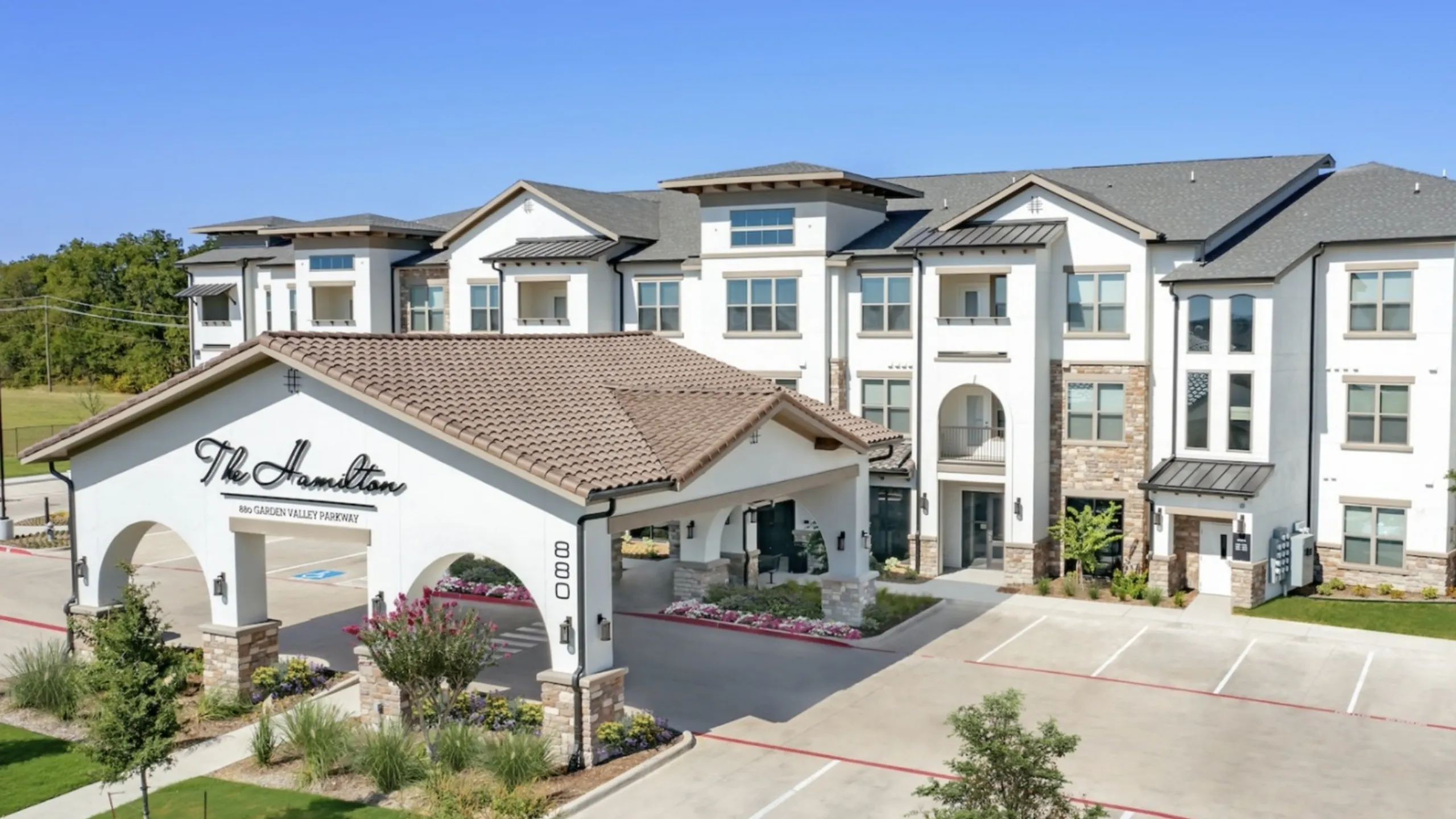Elegant exterior view of The Hamilton, showcasing modern architecture with a welcoming entrance and lush landscaping.