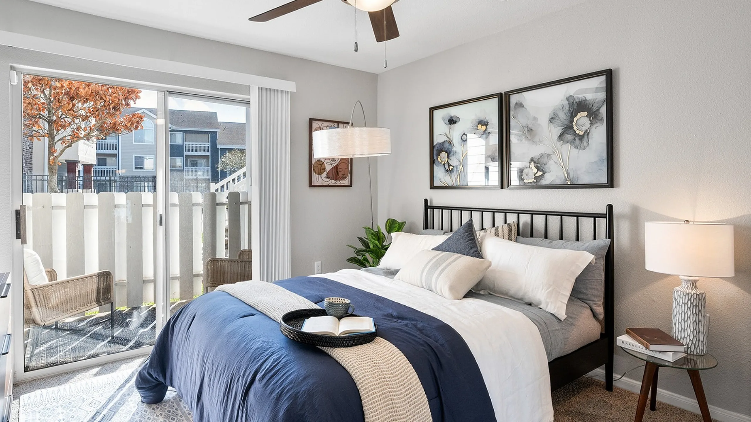 Elegant bedroom with a plush double bed and navy accents, featuring a sliding glass door opening to a serene patio view and modern decor.