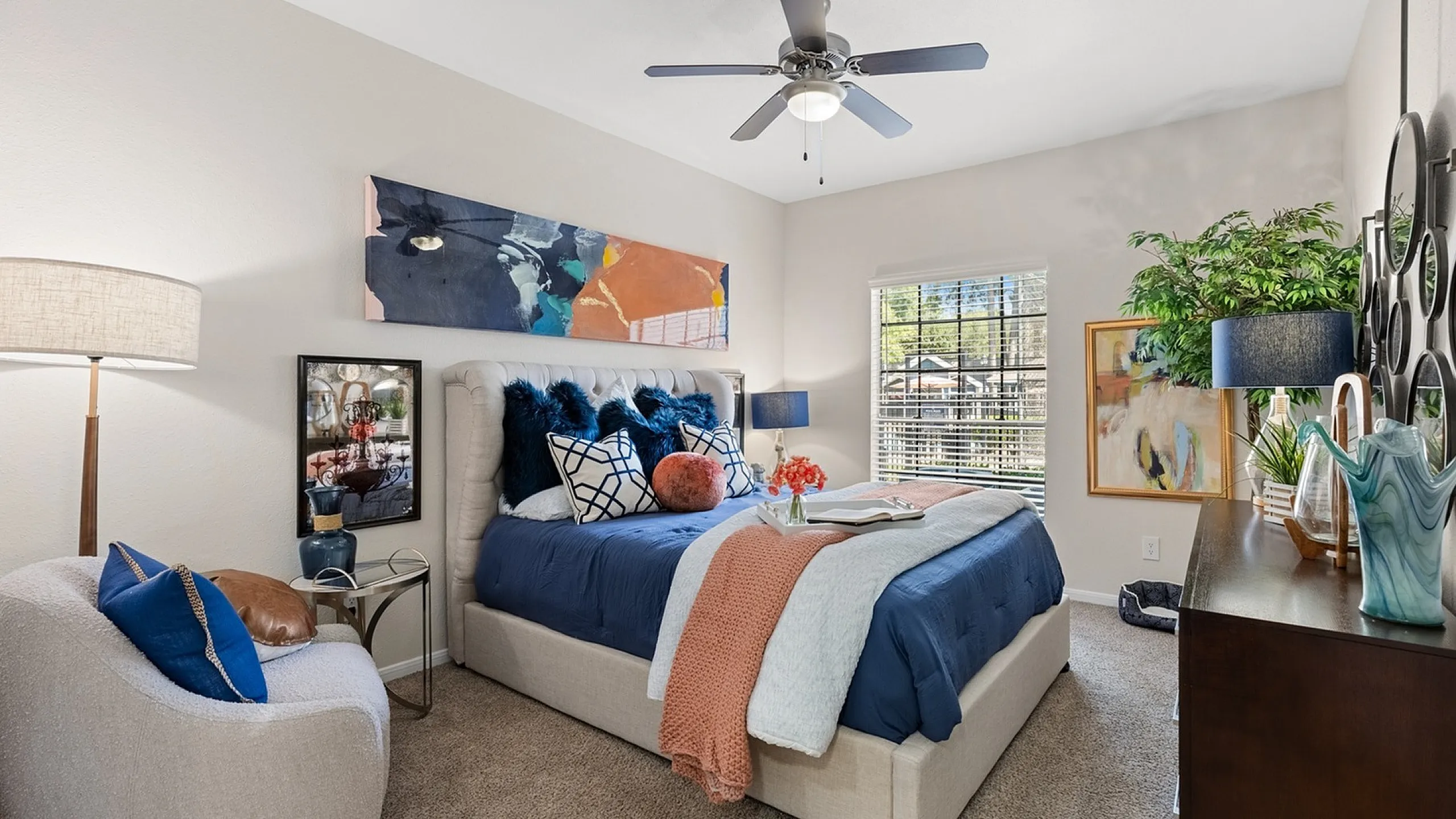 Inviting apartment community with a pristine blue pickleball court surrounded by lush greenery and stylish outdoor seating.