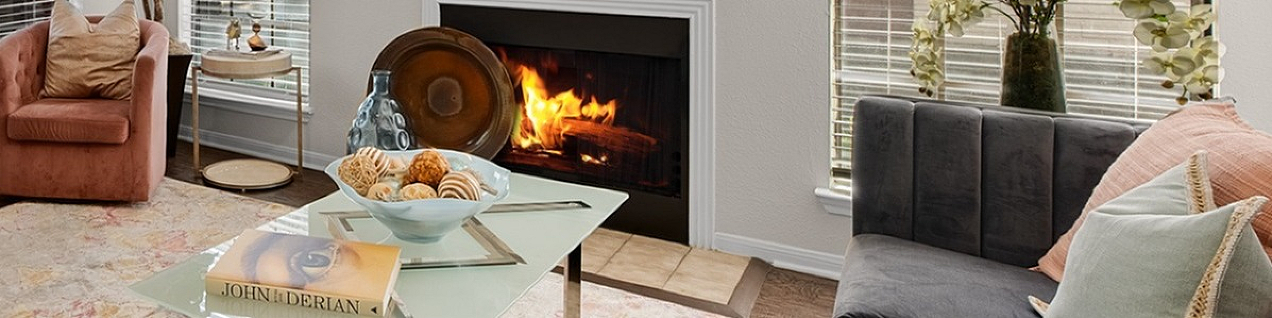 Cozy living room with a modern fireplace, elegant decor, lush plants, and plush seating for a warm and inviting atmosphere.
