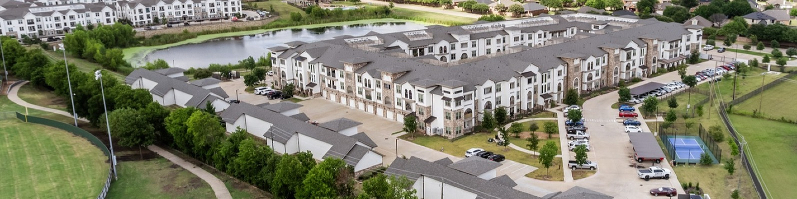 the hamilton at garden valley aerial view of the property with lake views and park land all around covered parking and garages ample parking 3 story building surrounds large outdoor amenity area
