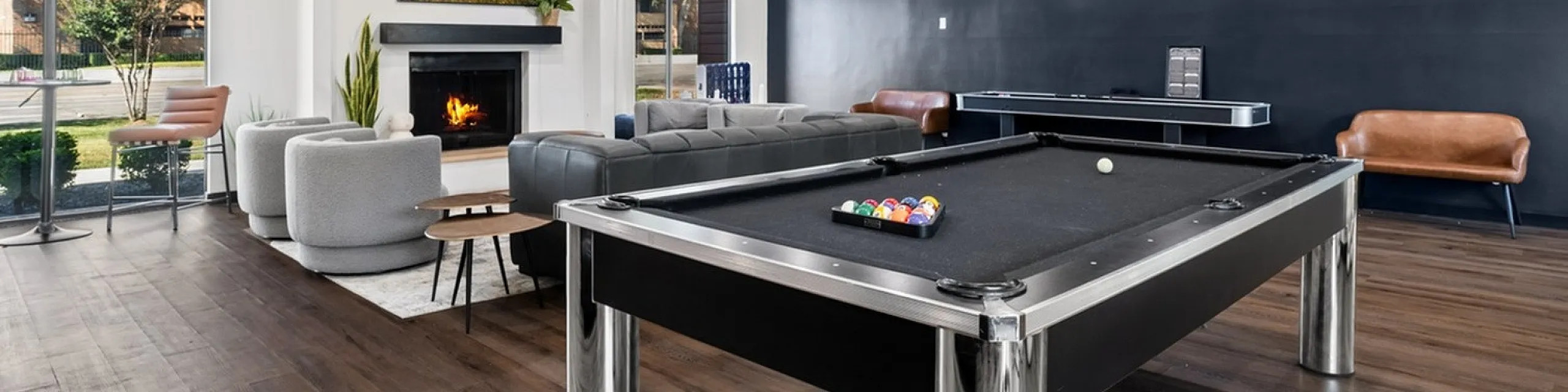 Elegant entertainment room featuring a sleek pool table, modern seating area, and a cozy fireplace, perfect for social gatherings.