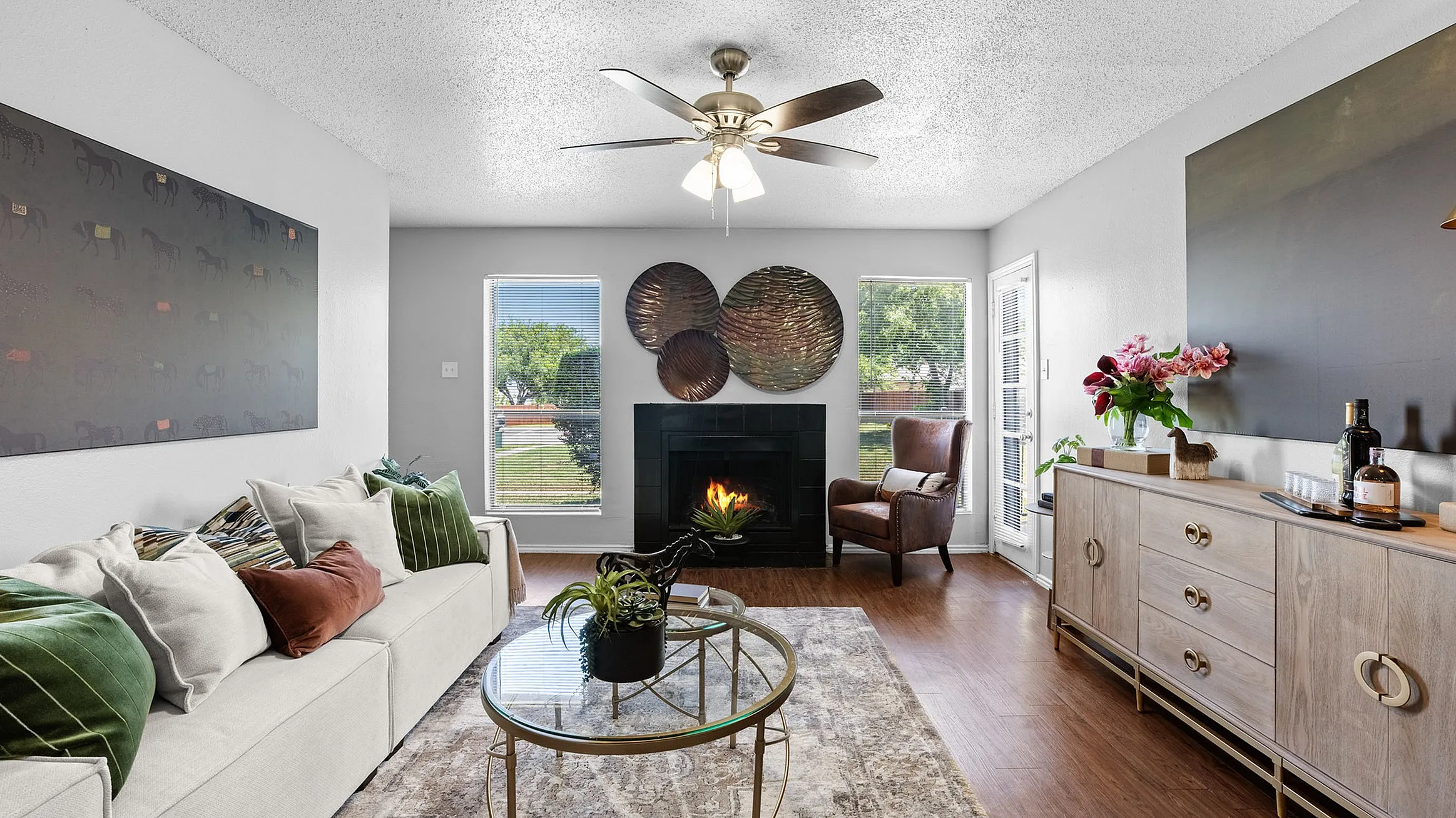Charming living room with cozy fireplace, plush seating, and elegant decor, offering natural light through large windows.