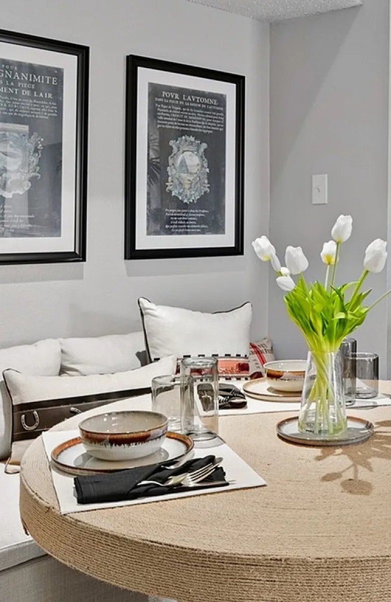 Chic living area showcasing a cozy sofa, elegant dining setup with tulips, and a modern kitchen with sleek appliances.