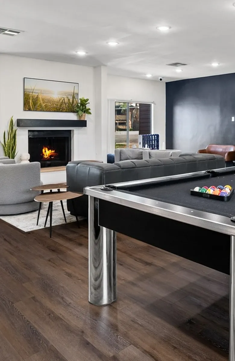 Luxurious apartment lounge featuring a modern pool table, elegant seating, and a cozy fireplace, perfect for relaxation and entertainment.