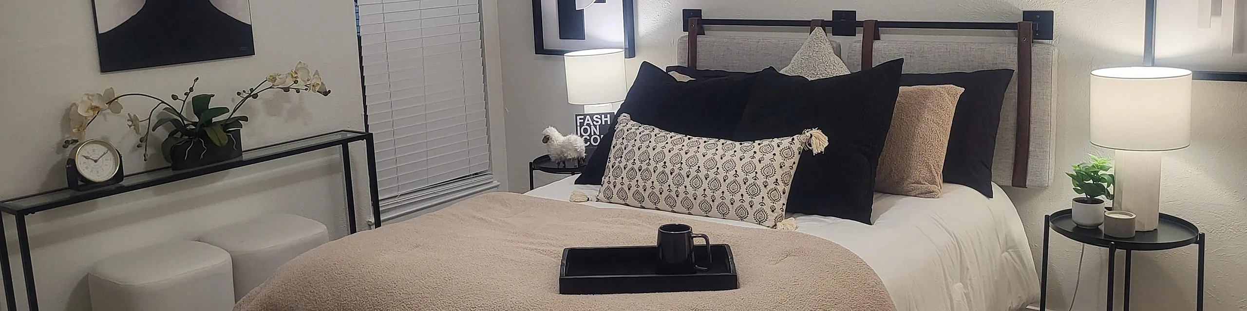 Elegant bedroom showcasing modern art, cozy bedding, and stylish decor with soft lighting and contemporary furnishings.
