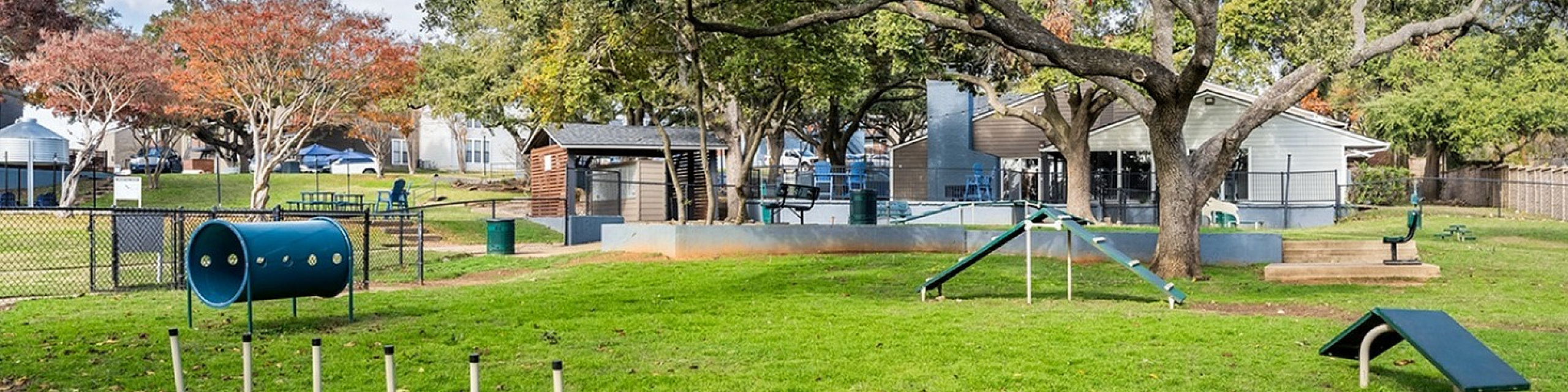 Charming residential park with lush green grass, mature trees, and a delightful play area for community enjoyment.