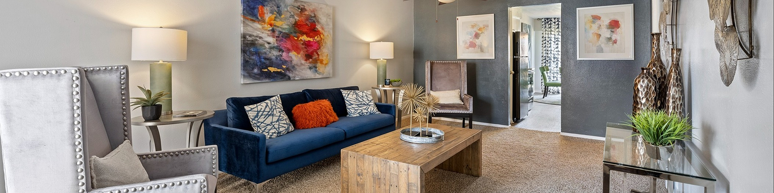 Modern living room with plush seating, vibrant artwork, and stylish decor featuring a wooden coffee table and soft lighting.