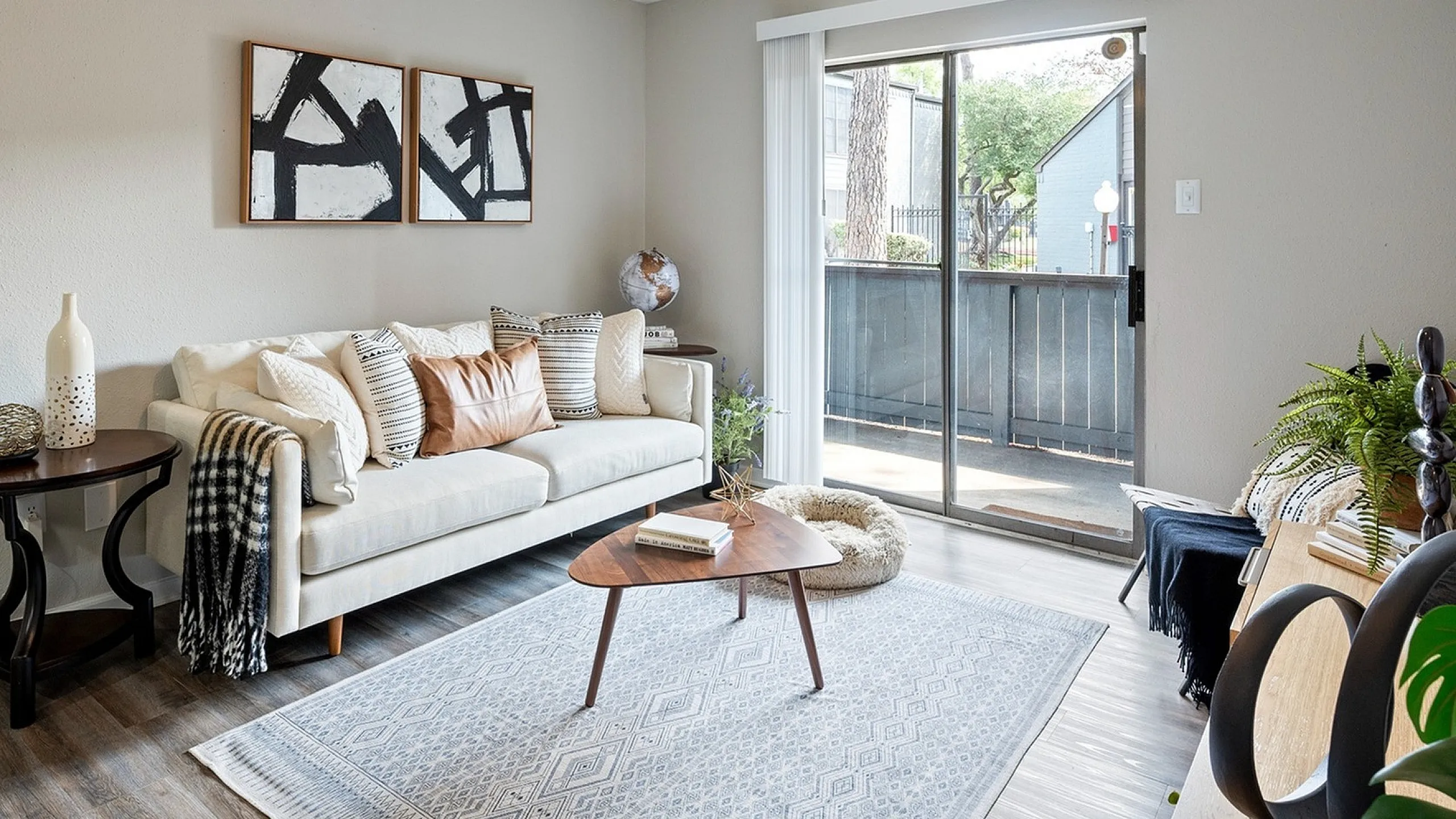 Inviting living room with modern decor, comfy sofa, ceiling fan, and glass doors leading to a lovely outdoor view.
