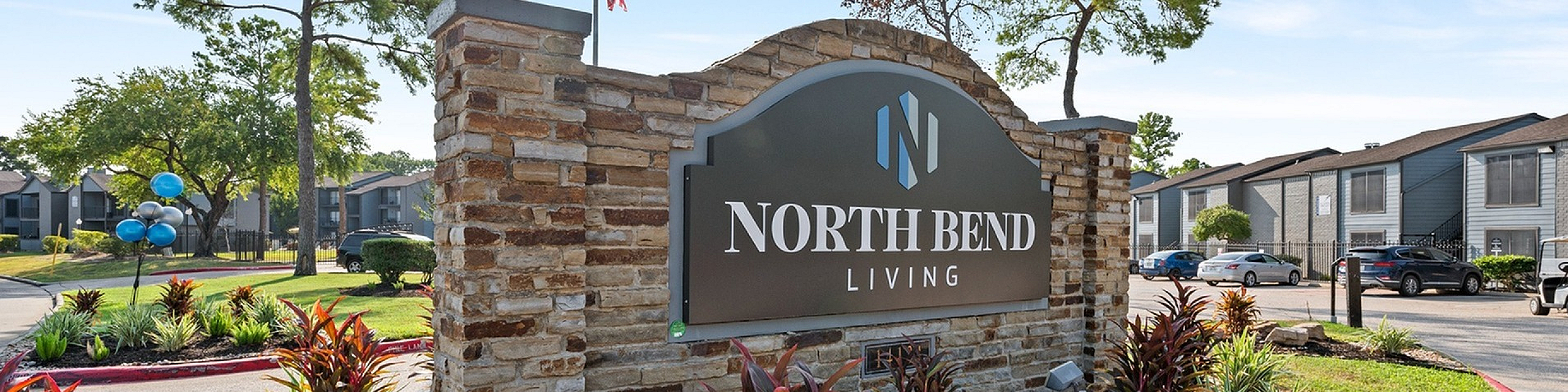 Inviting entrance to North Bend Living adorned with beautiful landscaping and a welcoming sign, under a clear blue sky.