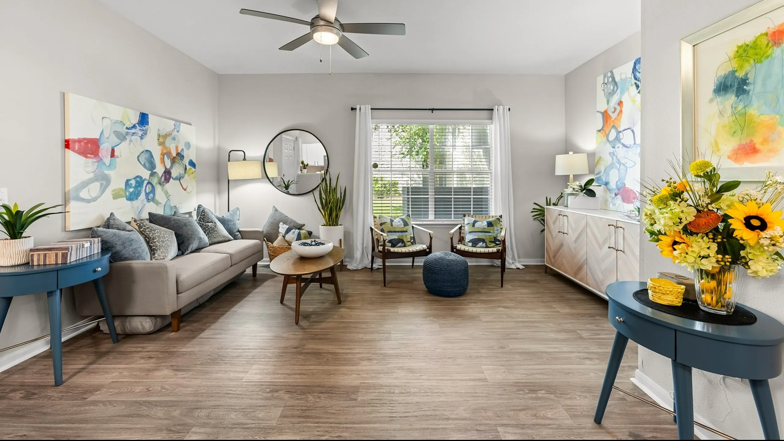 Bright and inviting living room with elegant decor, featuring a comfortable sofa, modern art, and abundant natural light.
