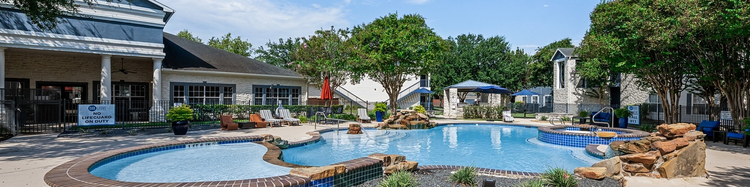 Inviting outdoor pool area surrounded by lush greenery and elegant stonework, perfect for relaxation and leisure.
