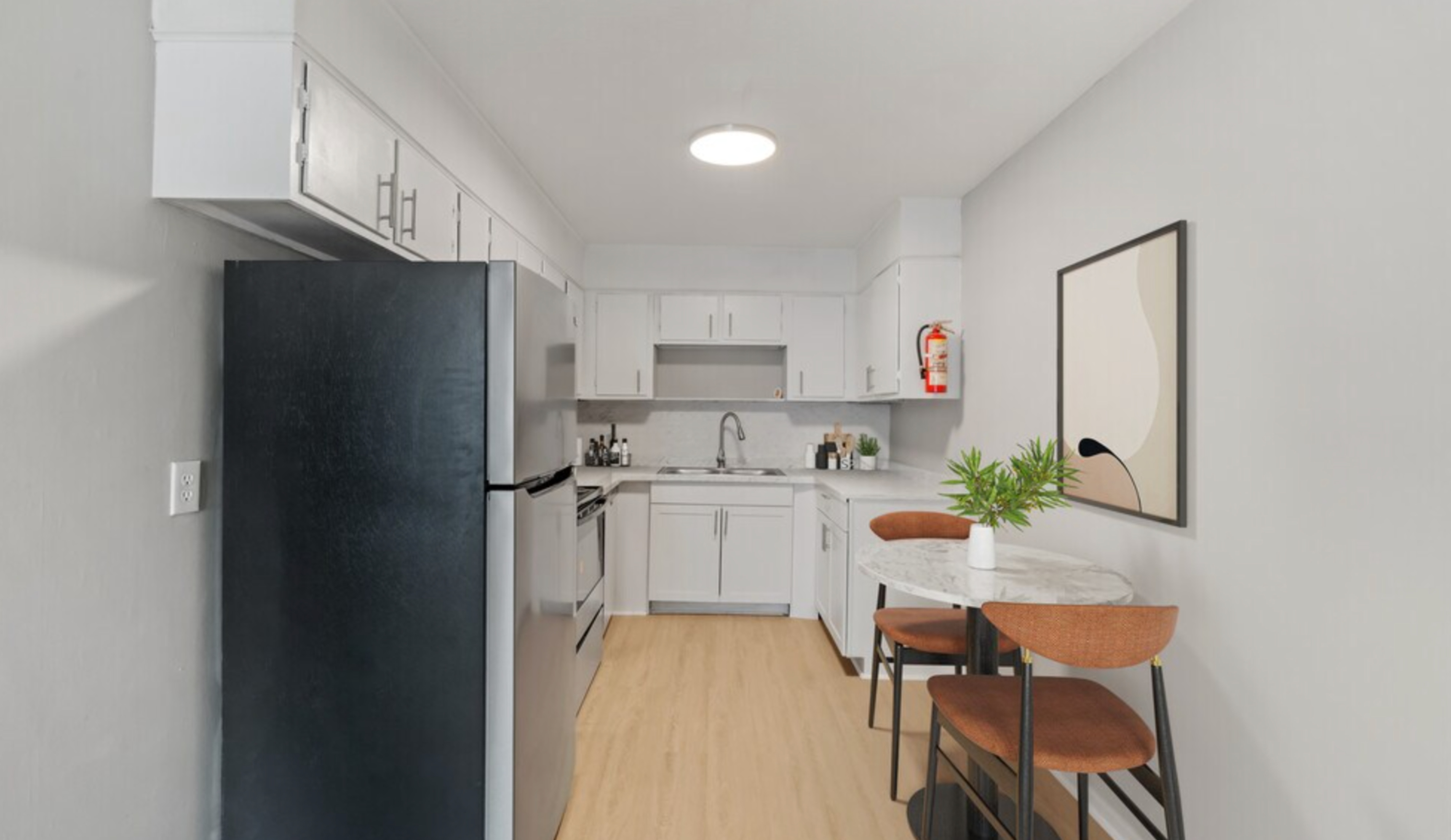 Chic kitchen with sleek white cabinets, modern appliances, and a cozy dining area featuring stylish seating and contemporary decor.
