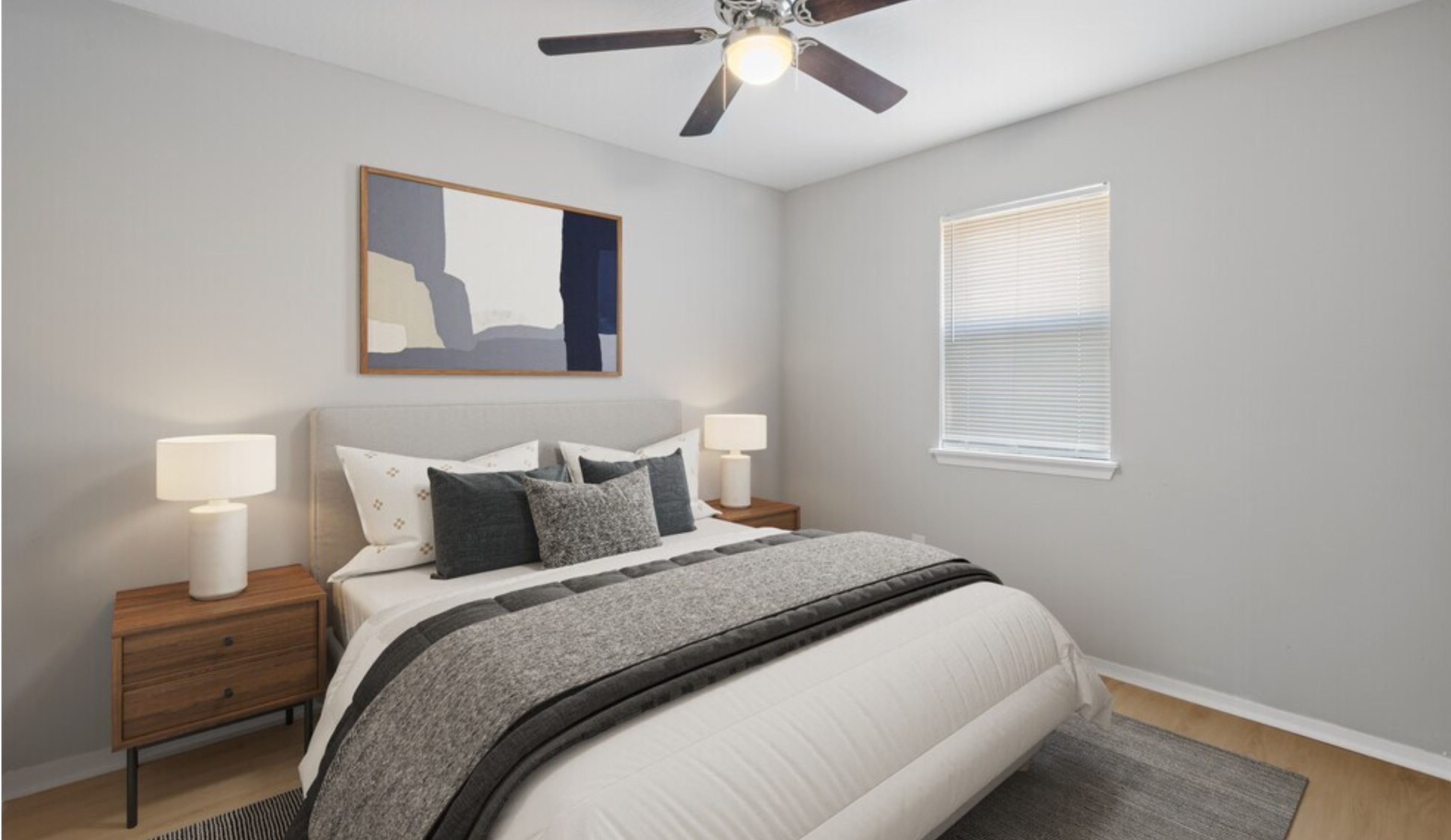 Elegant bedroom with modern decor featuring a cozy queen bed, stylish nightstands, and a ceiling fan, illuminated by soft natural light.