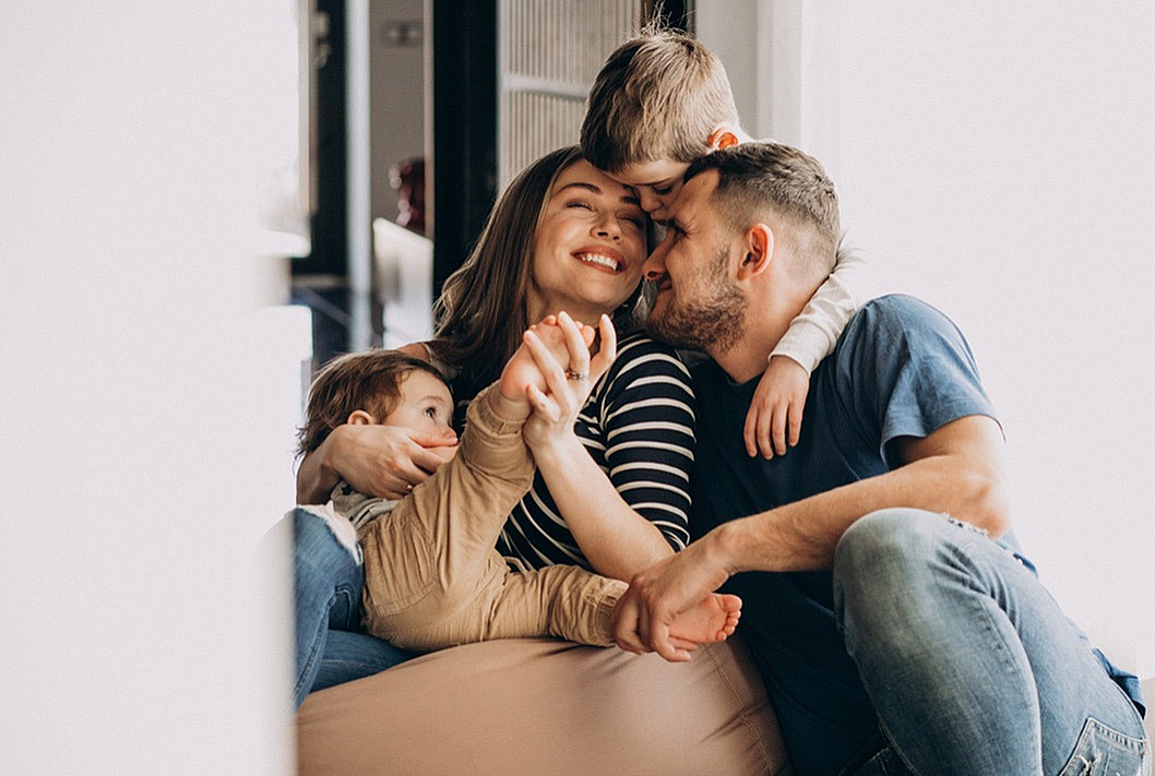 A joyful family of four shares a warm, loving moment in their cozy home with plenty of natural light.
