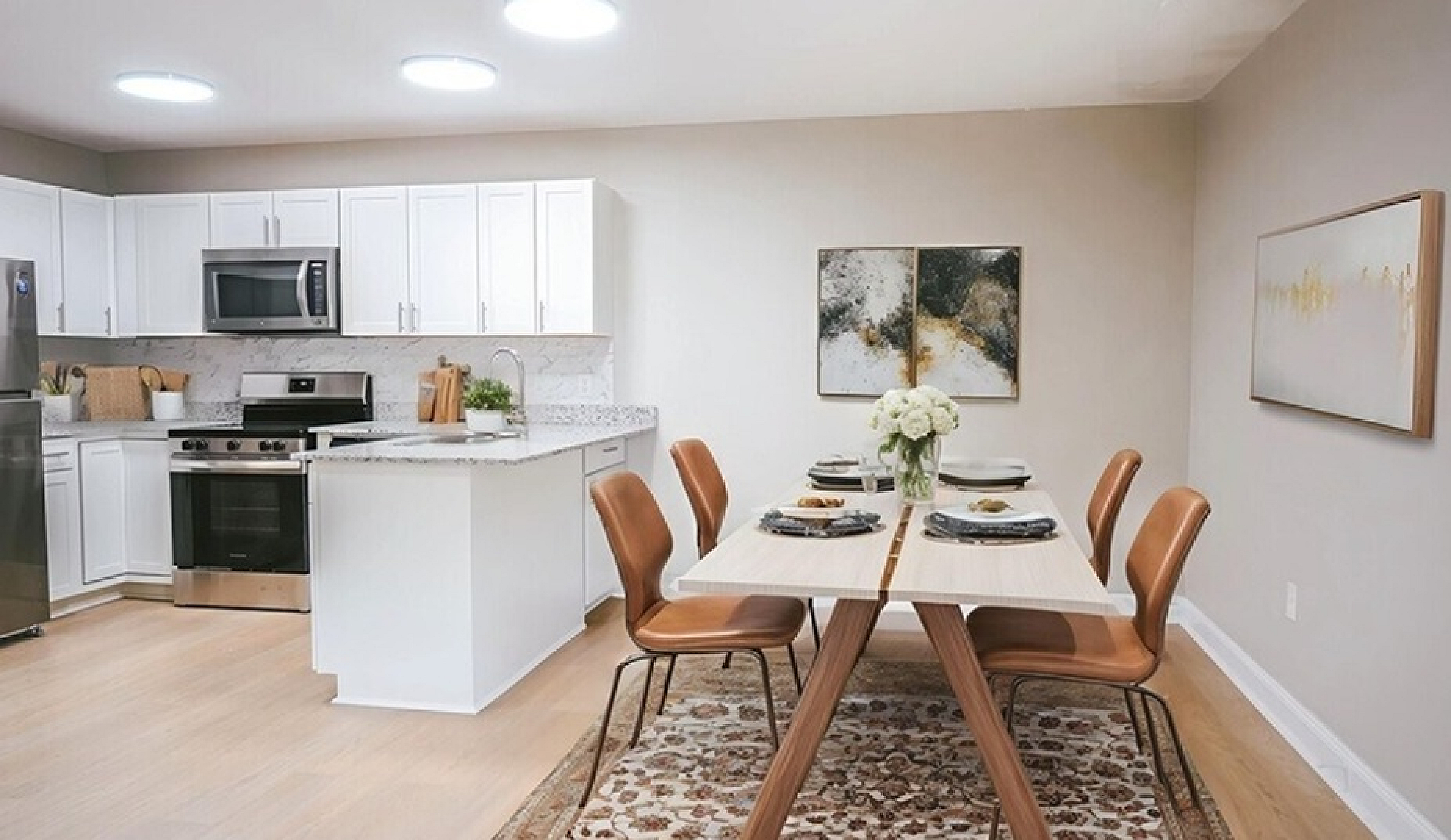 Bright, modern kitchen and dining area with sleek white cabinetry, stainless steel appliances, and a cozy dining table set for four.