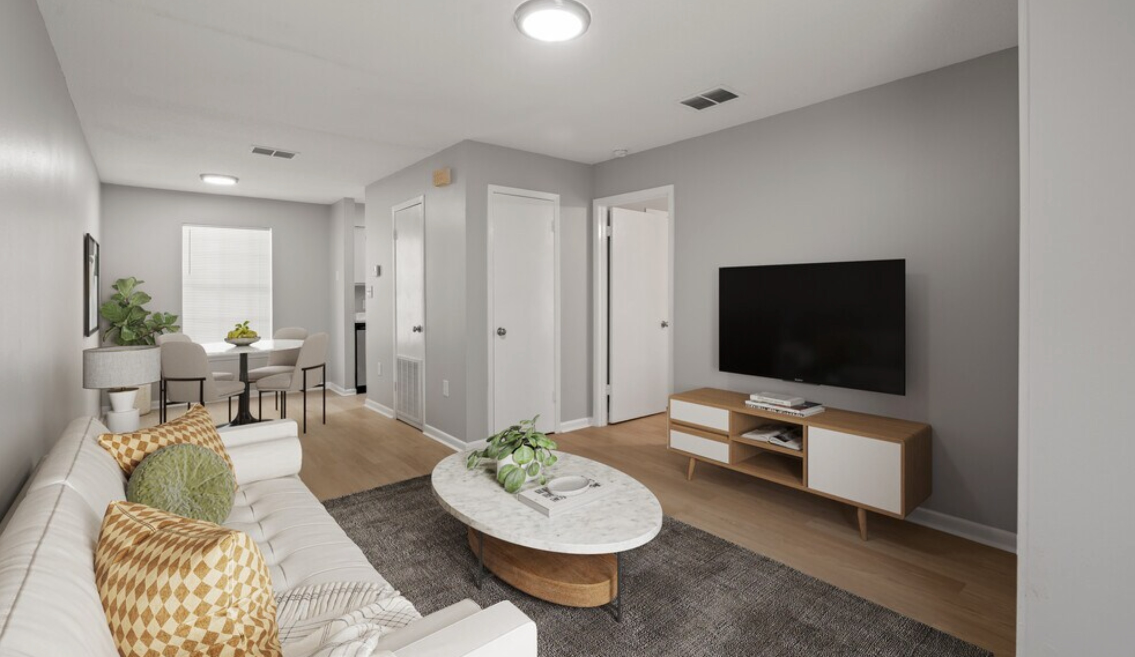 Elegant living room with modern decor, featuring a cozy white sofa, stylish marble coffee table, and mounted flat-screen TV, complemented by a dining area and natural lighting.