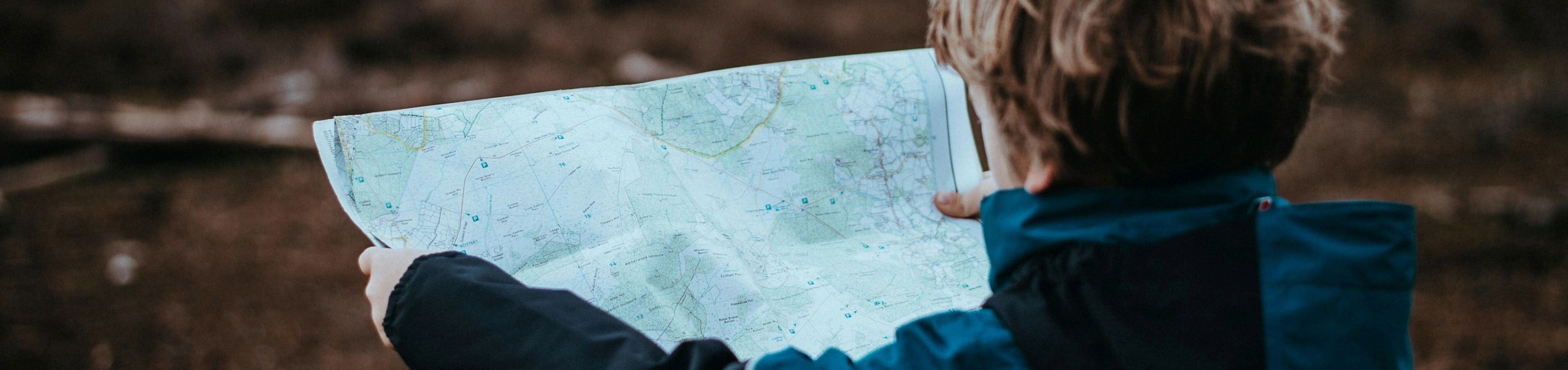 Child exploring nature with a map, embodying adventure and curiosity in a serene outdoor setting.