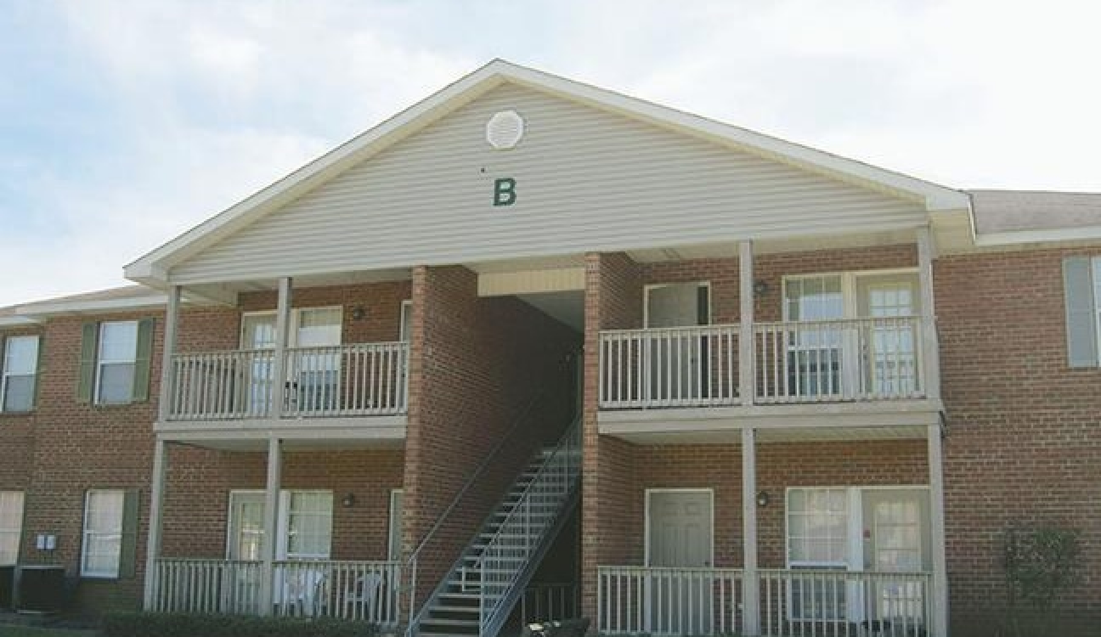 Charming brick apartment complex with spacious balconies and lush green surroundings.