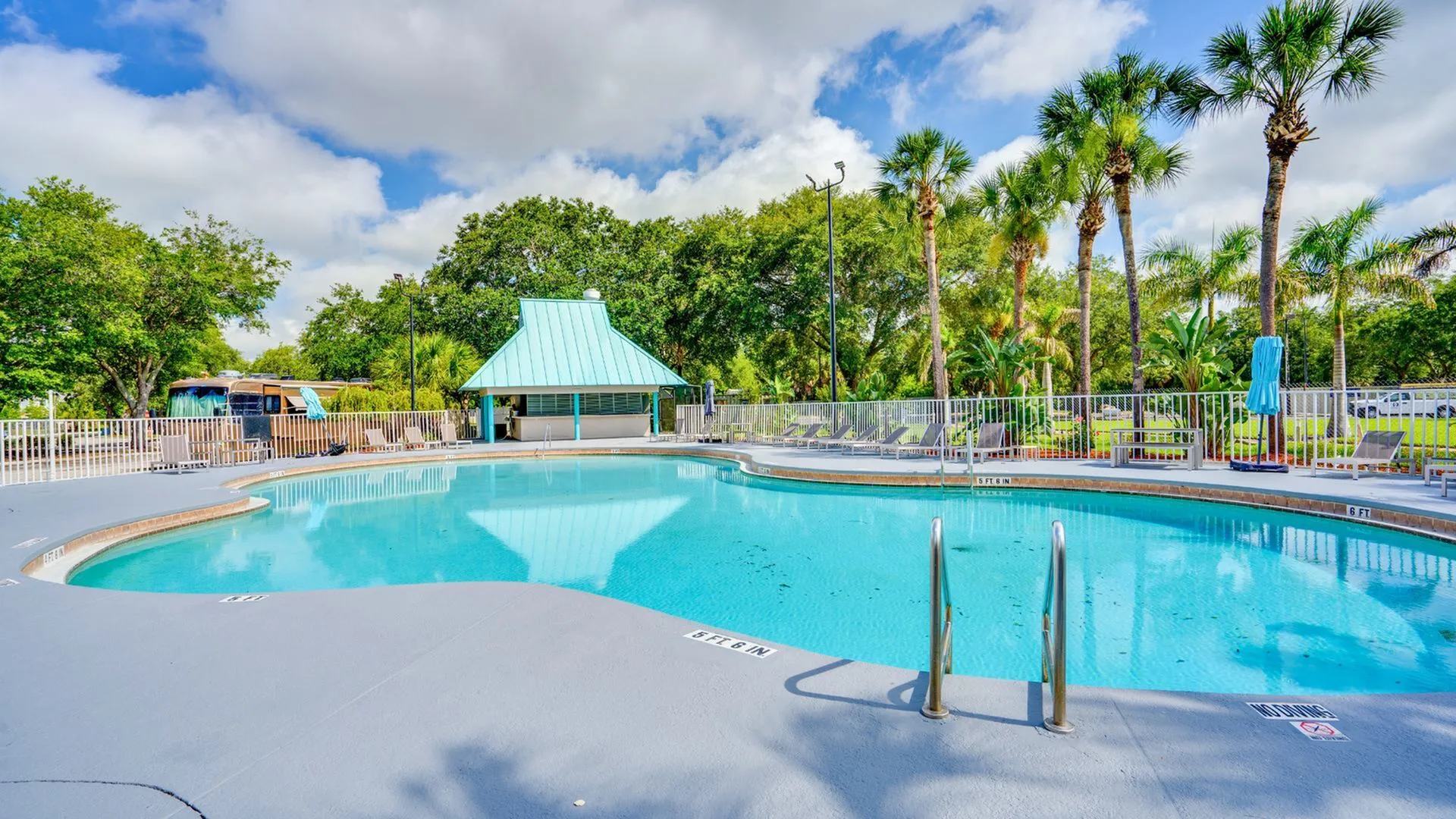 Inviting outdoor swimming pool surrounded by lush greenery and swaying palm trees, perfect for relaxation and leisure.