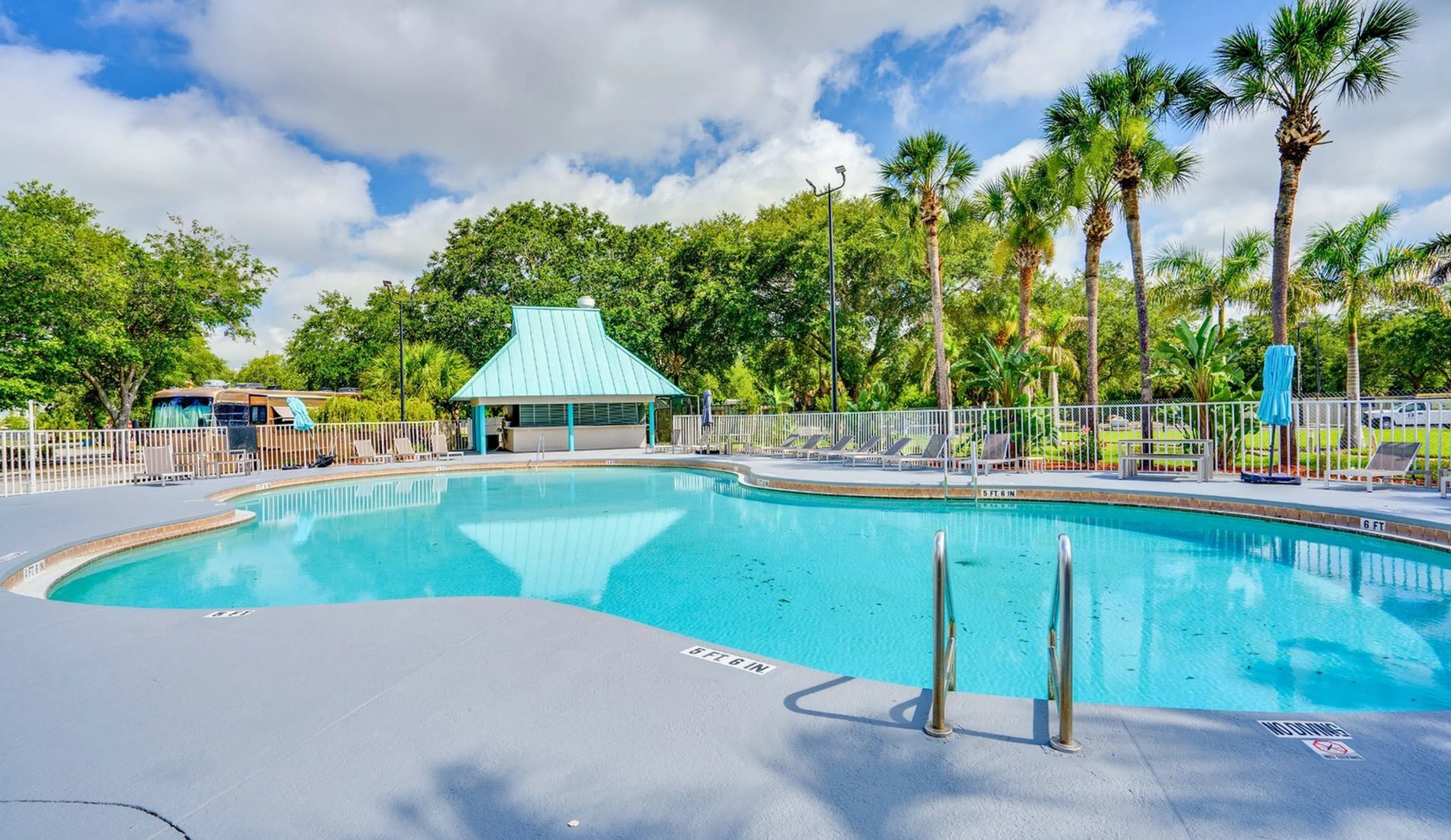 Inviting outdoor pool area with lush palm trees and bright blue skies, perfect for relaxation and leisure.