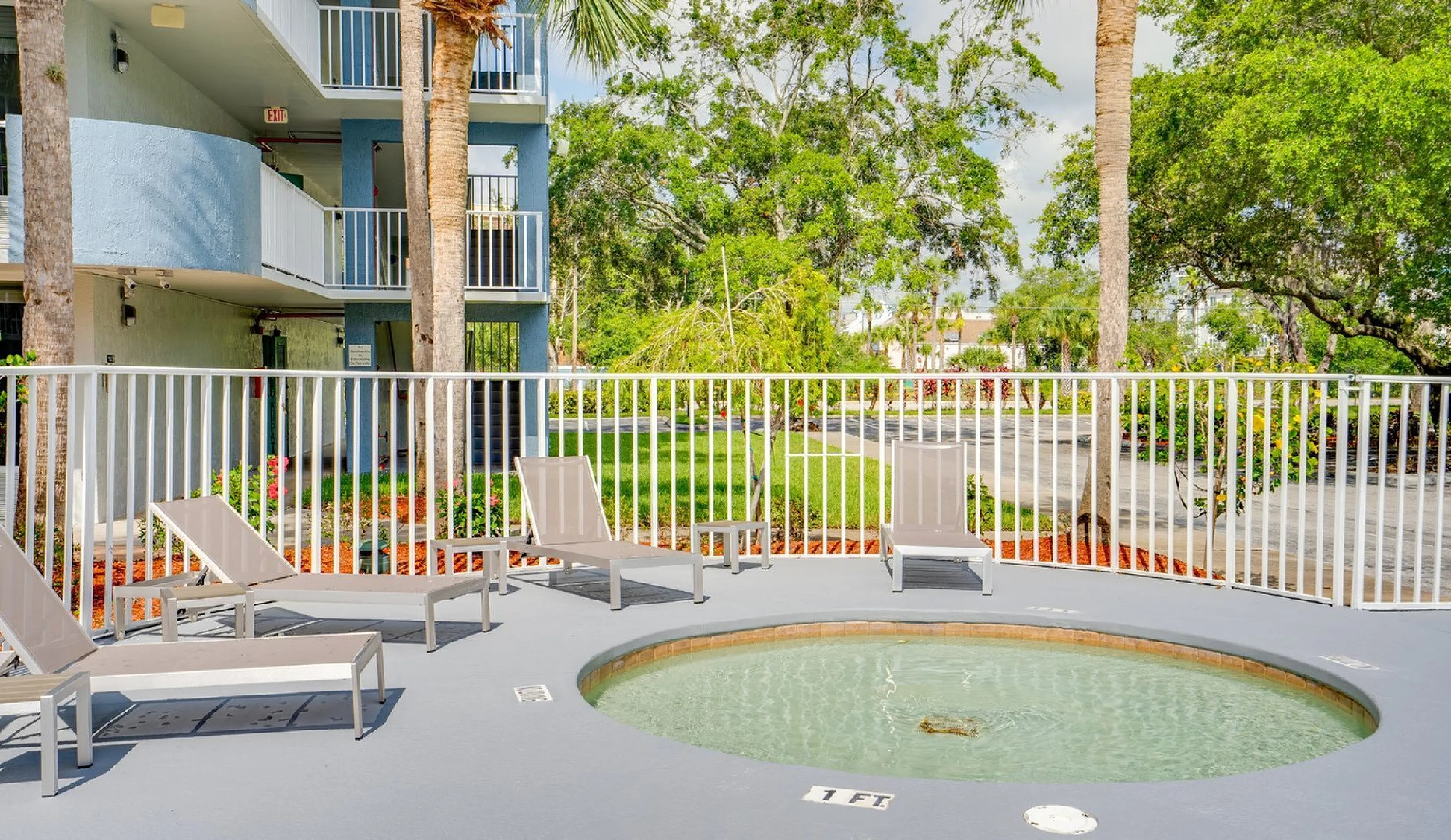 Inviting outdoor area with a cozy round hot tub, surrounded by sun loungers and lush greenery.