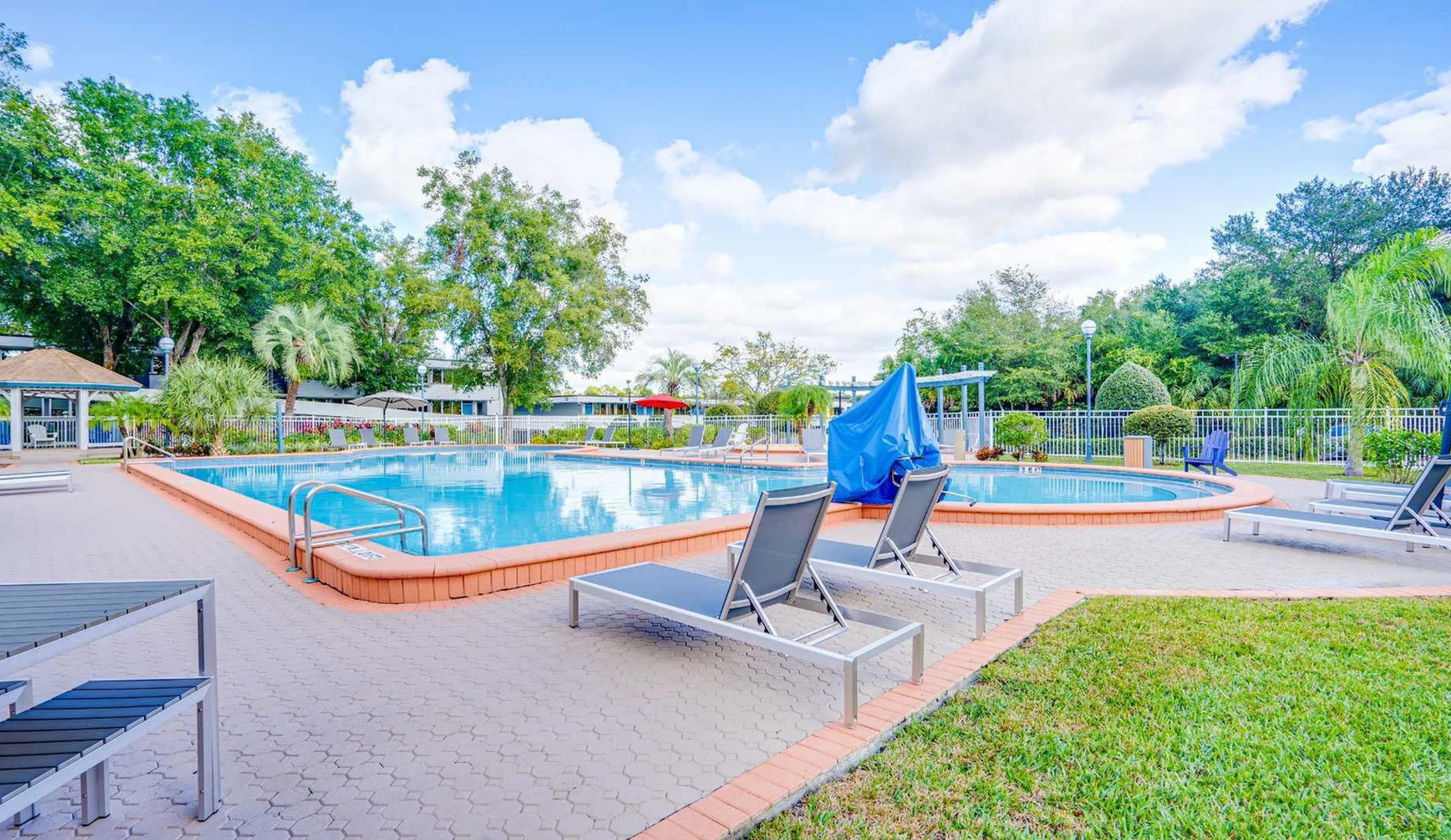 Inviting outdoor pool area with lush greenery and lounge chairs, perfect for relaxation and leisure.
