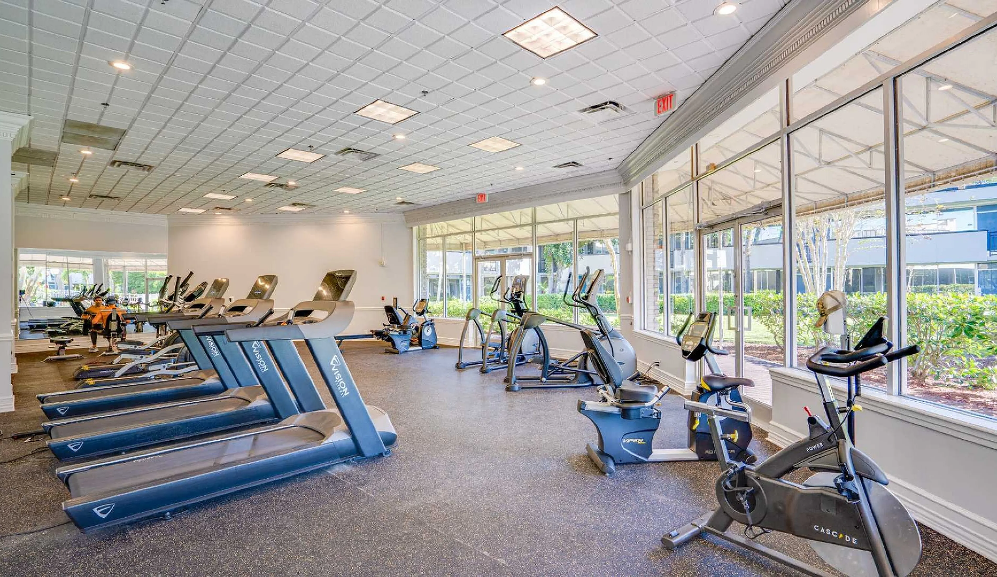 Bright and modern fitness center with state-of-the-art equipment and large windows overlooking lush greenery.
