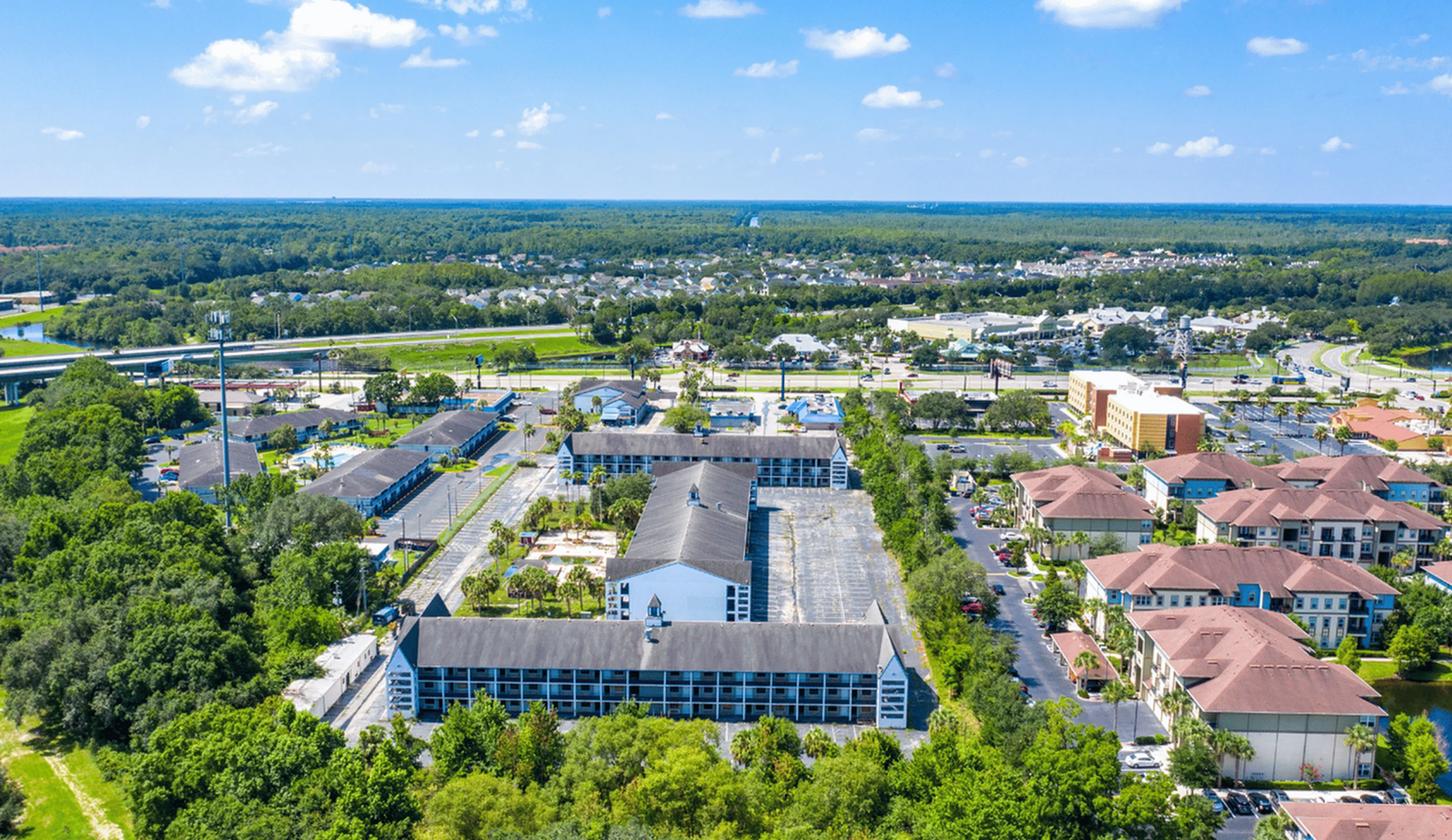 Vibrant aerial view of a well-planned residential area surrounded by lush greenery, showcasing modern apartment complexes and convenient road access.