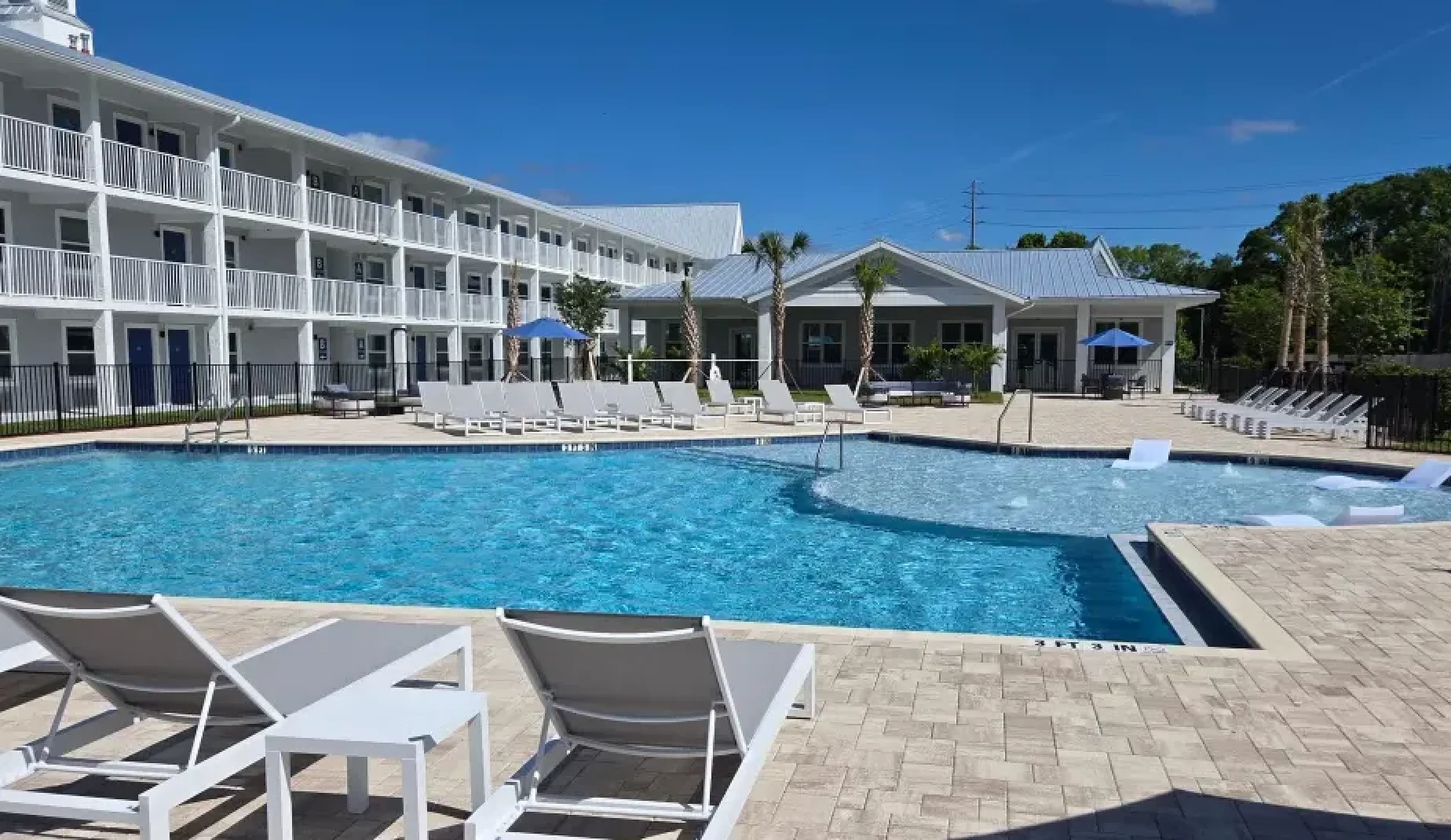 Elegant apartment complex in Kissimmee, Florida showcasing modern architecture with spacious balconies and palm-lined parking area.