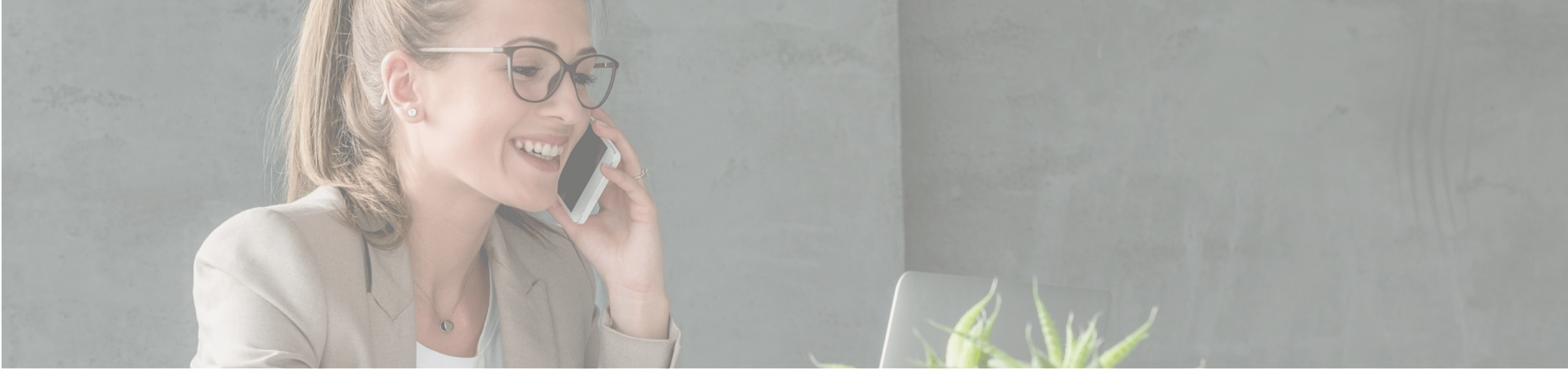 Professional woman in a stylish office environment, confidently on the phone with a laptop and plant nearby.
