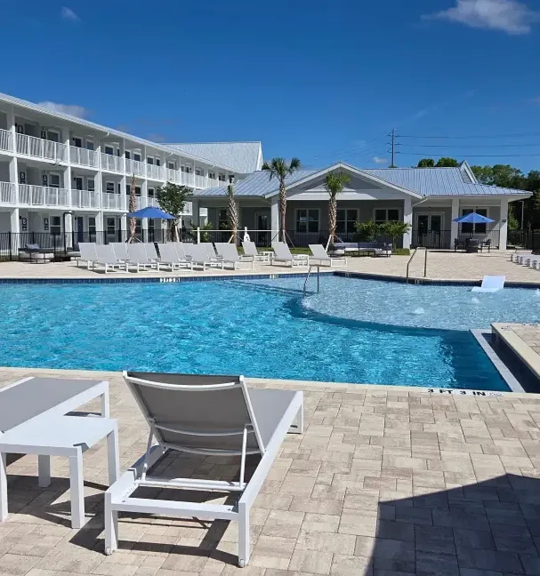 Elegant apartment complex in Kissimmee, Florida showcasing modern architecture with spacious balconies and palm-lined parking area.
