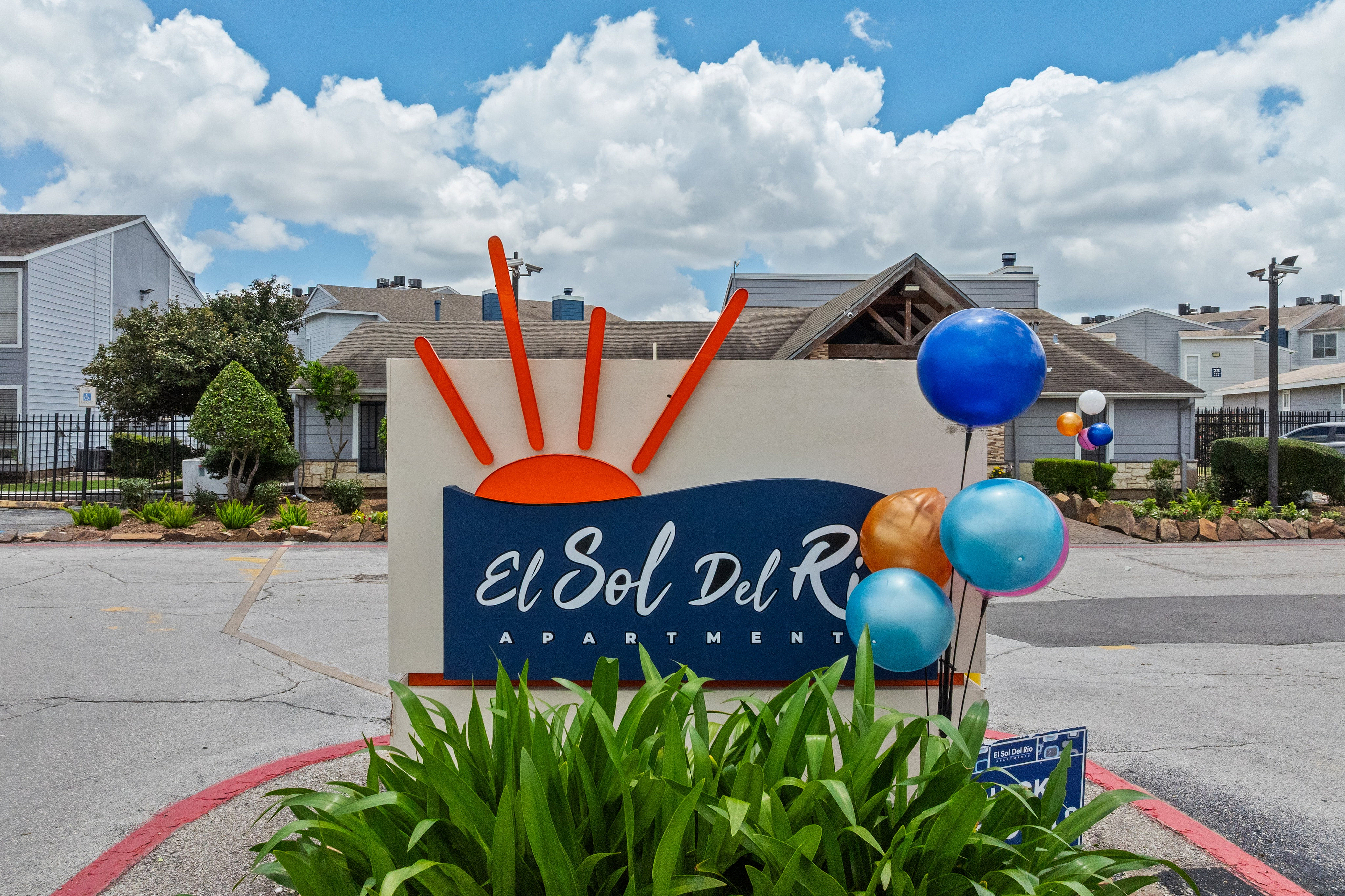 Welcoming entrance of El Sol Del Rio Apartments with vibrant balloons and clear blue skies.
