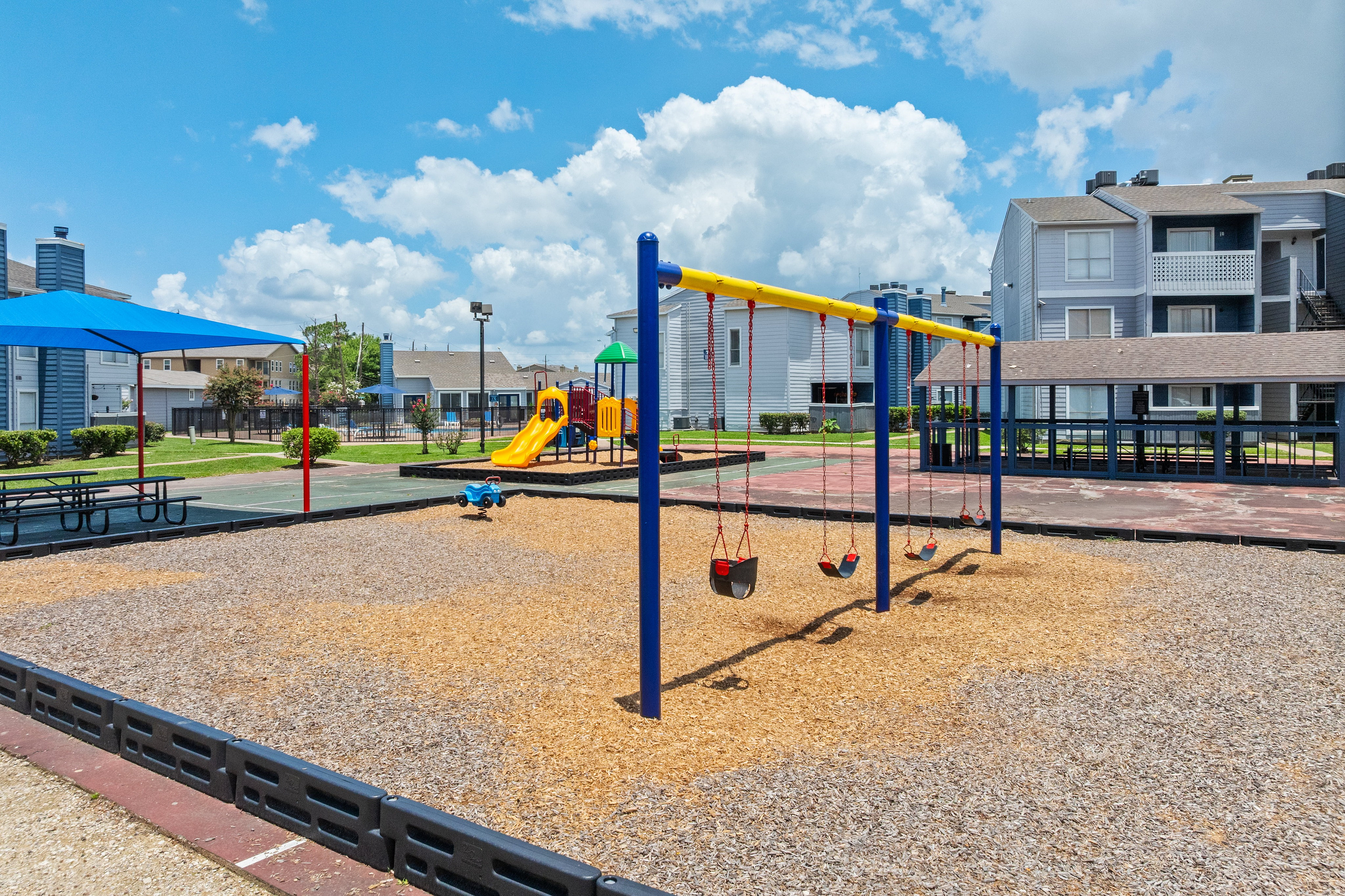Inviting outdoor playground with swings and slides, nestled within a vibrant apartment community for family-friendly living.