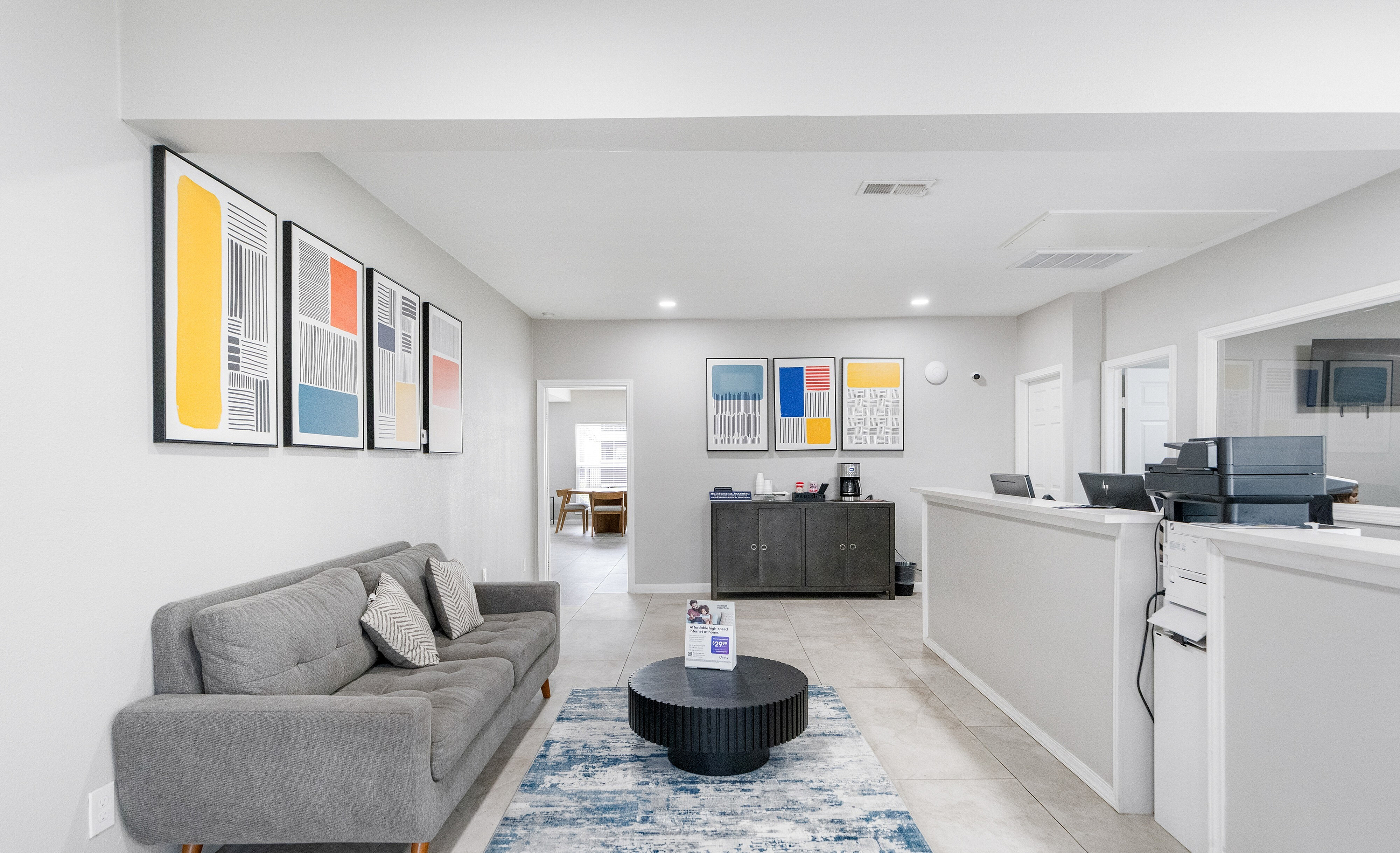 Modern office space featuring a stylish gray sofa, abstract wall art, and a cozy ambiance with natural light.
