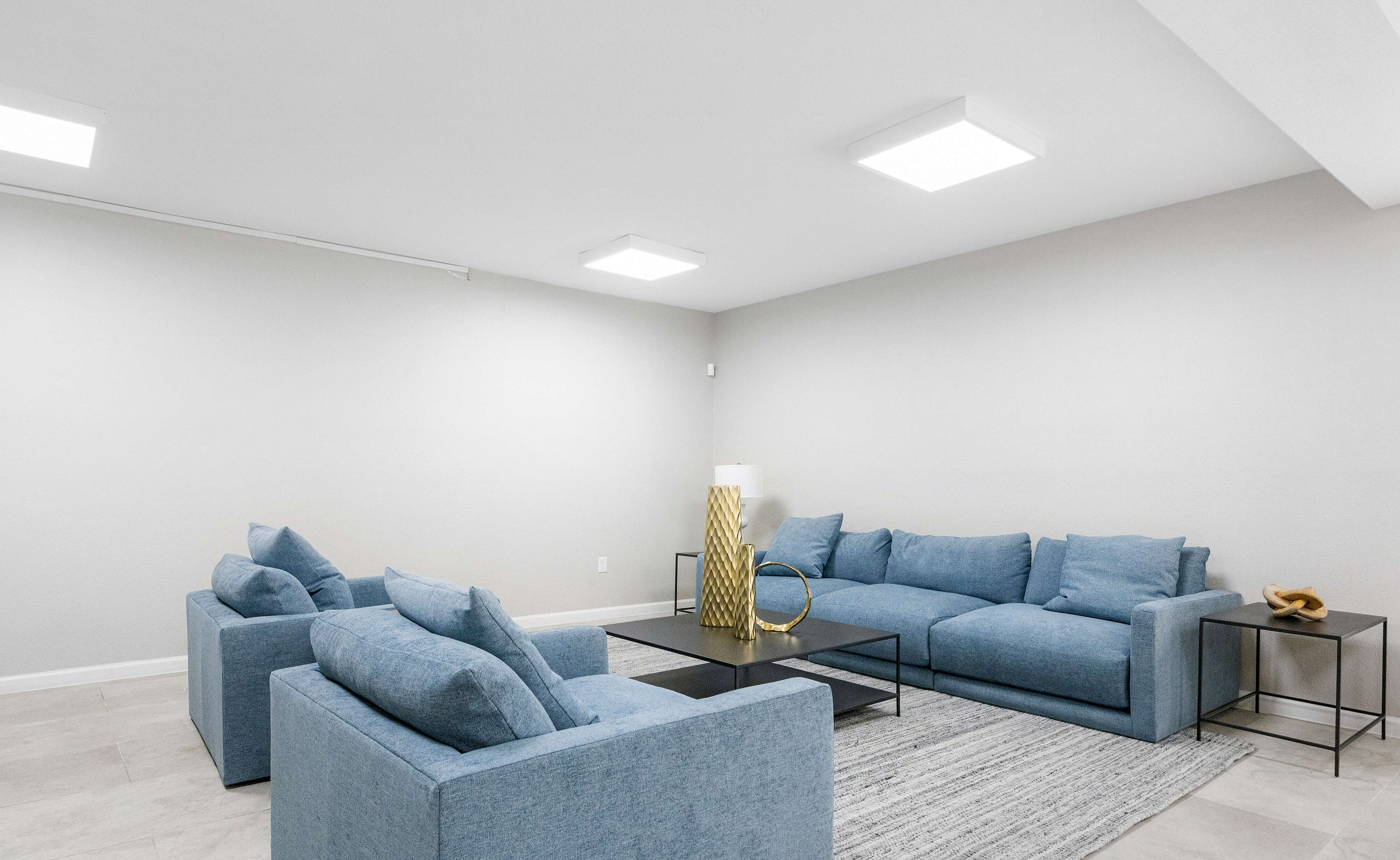 Modern living room with stylish blue couches, sleek decor, and soft gray walls offering a serene ambiance.