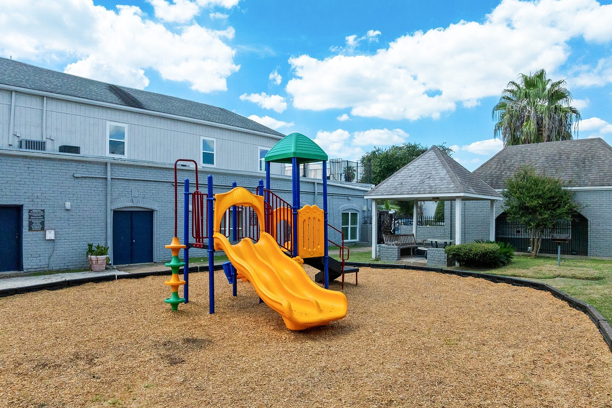 Charming apartment playground with vibrant slides and shady gazebo, ideal for family relaxation and outdoor fun.