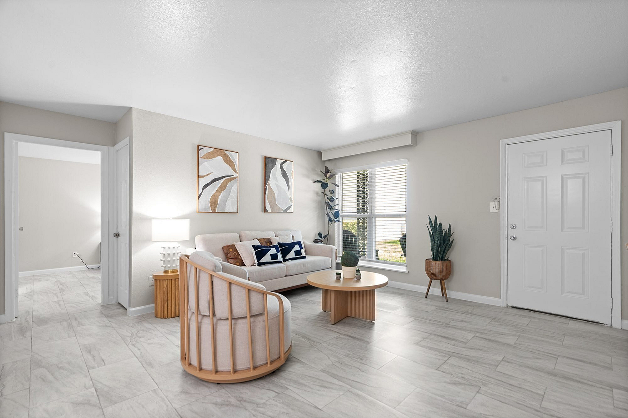 Bright and modern living room with elegant decor, plush seating, and large windows overlooking greenery.