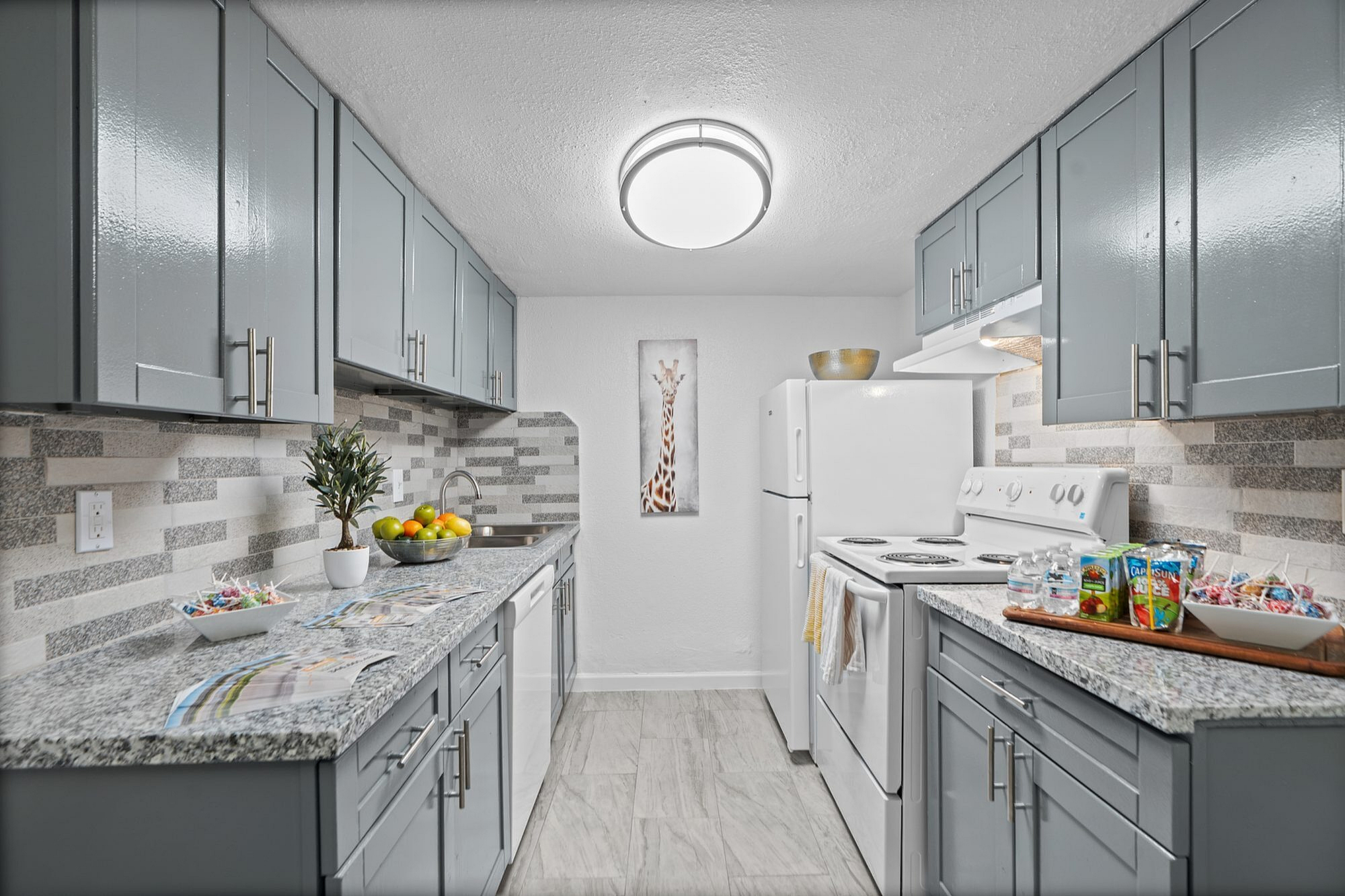 Modern kitchen with sleek gray cabinets, elegant granite countertops, stylish backsplash, and ambient lighting creating a sophisticated ambiance.