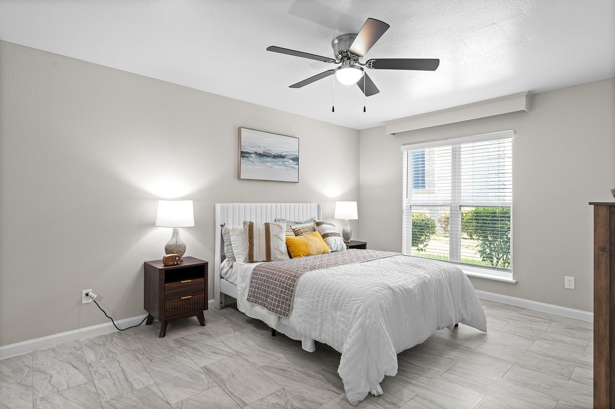 Bright and inviting bedroom with modern decor, large window allowing natural light, and cozy furnishings.