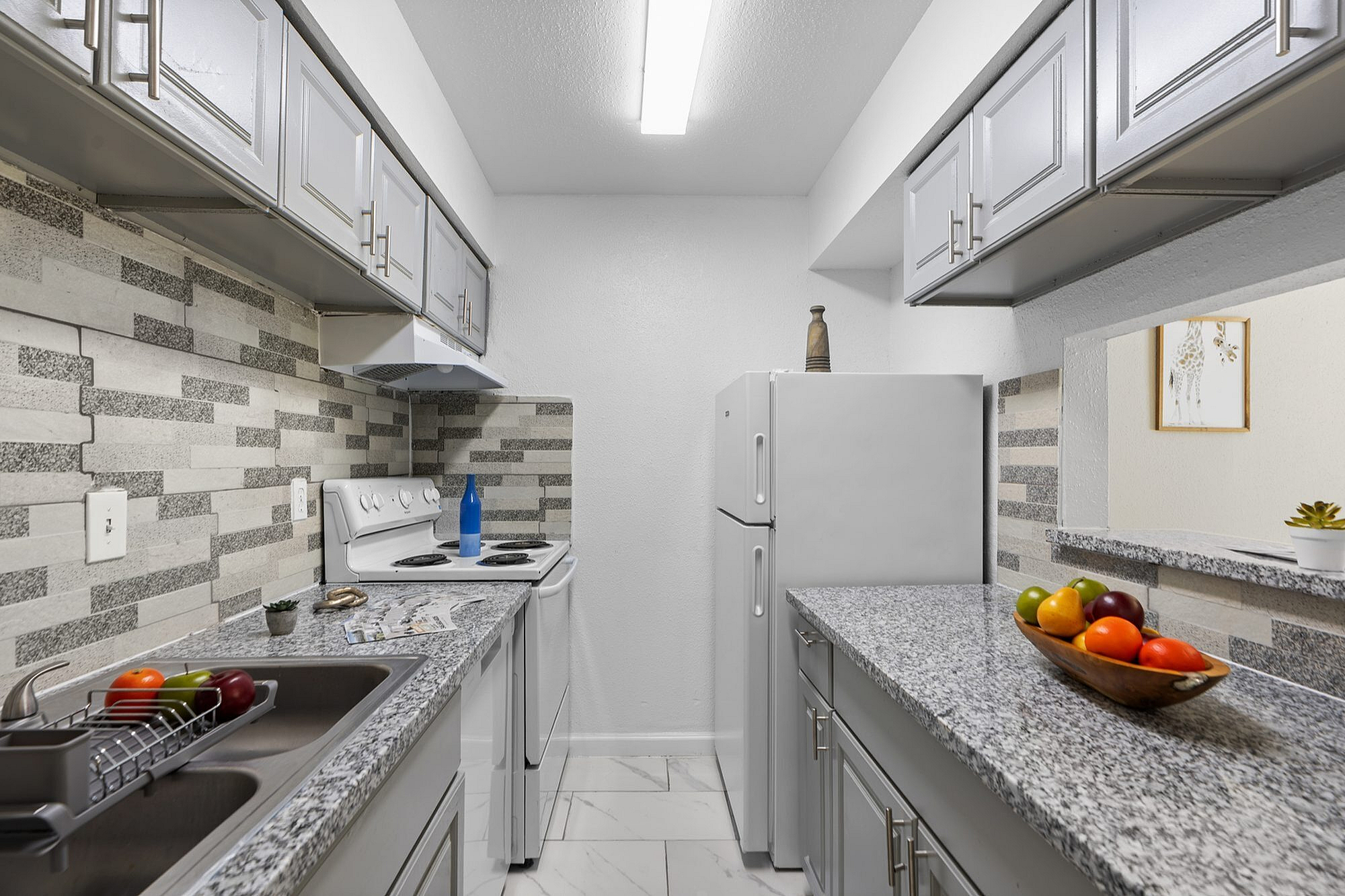 Modern kitchen with sleek granite countertops, stylish cabinetry, and bright tile backsplash.