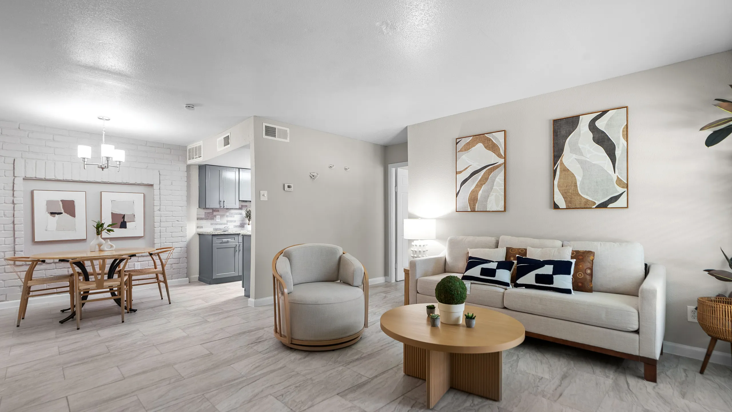 Modern apartment living room featuring sleek gray cabinetry in the kitchen, elegant dining area with contemporary art, and cozy seating arrangement with stylish decor.