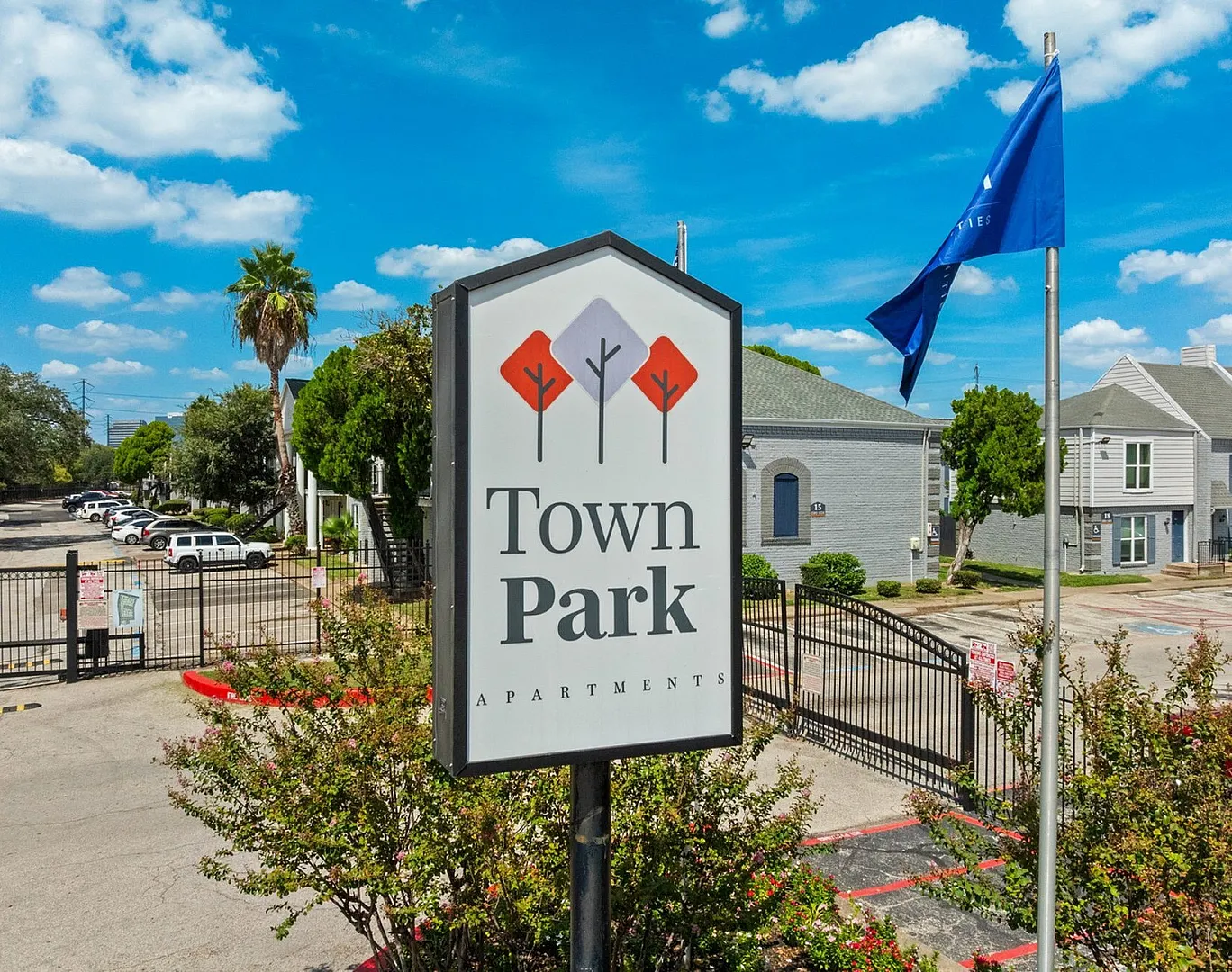 Inviting entrance of Town Park Apartments featuring a clear blue sky, lush greenery, and modern architecture.