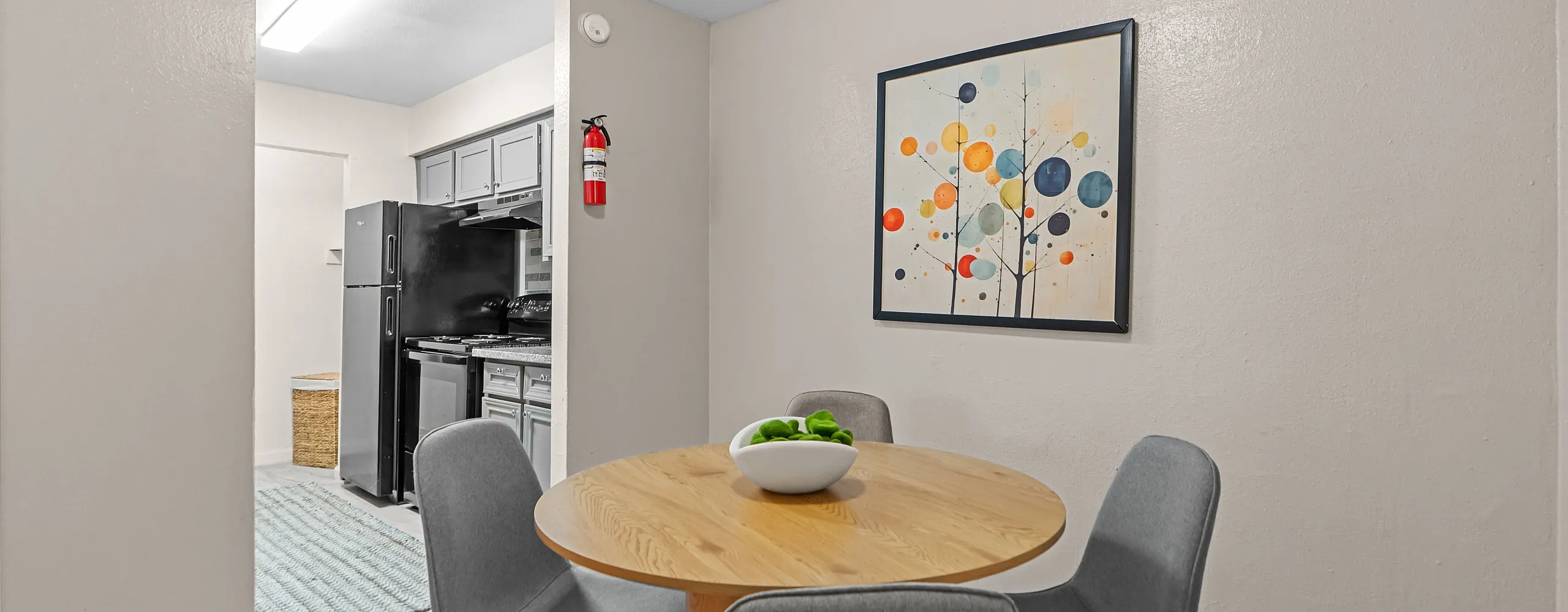 Chic dining area with a modern round table and plush chairs, leading to a sleek kitchen with contemporary appliances.