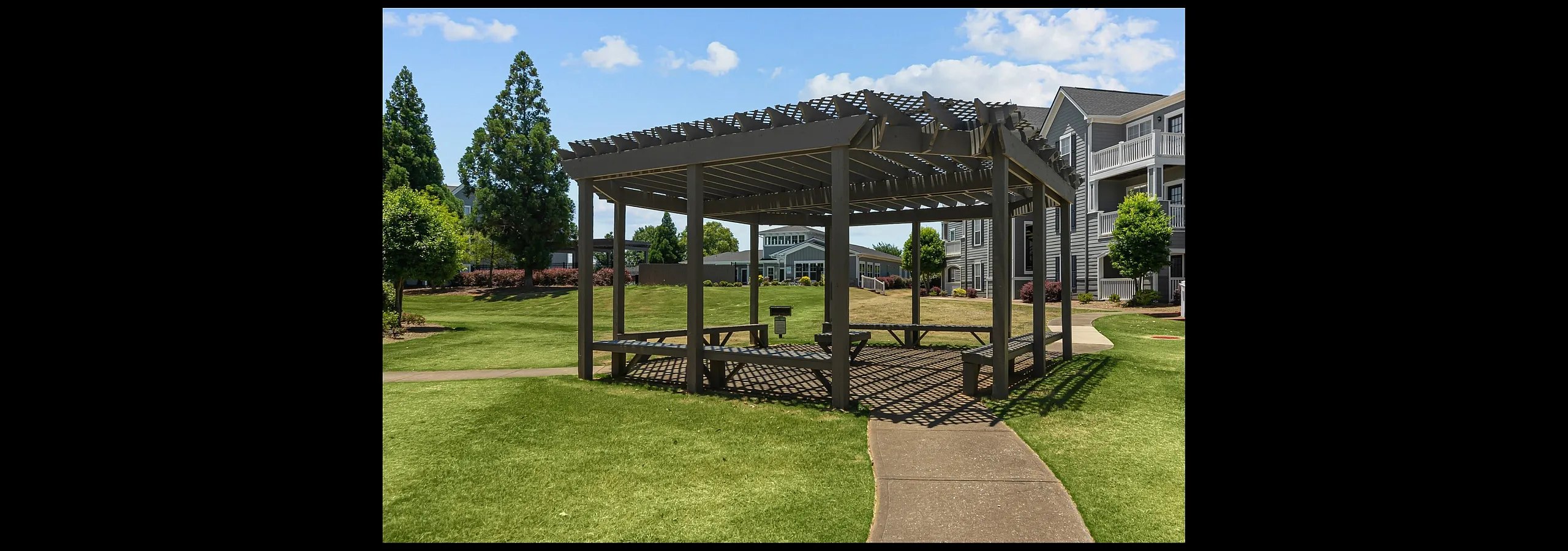 Charming gazebo in lush green apartment courtyard, offering a perfect outdoor retreat with picturesque views.