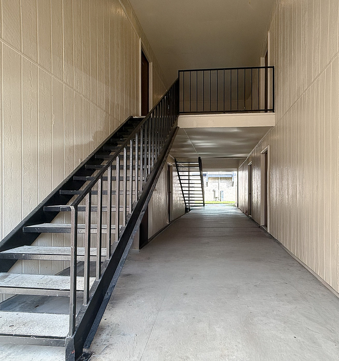 Inviting apartment corridor with clean, modern design and sturdy metal stairway leading to upper level residences.