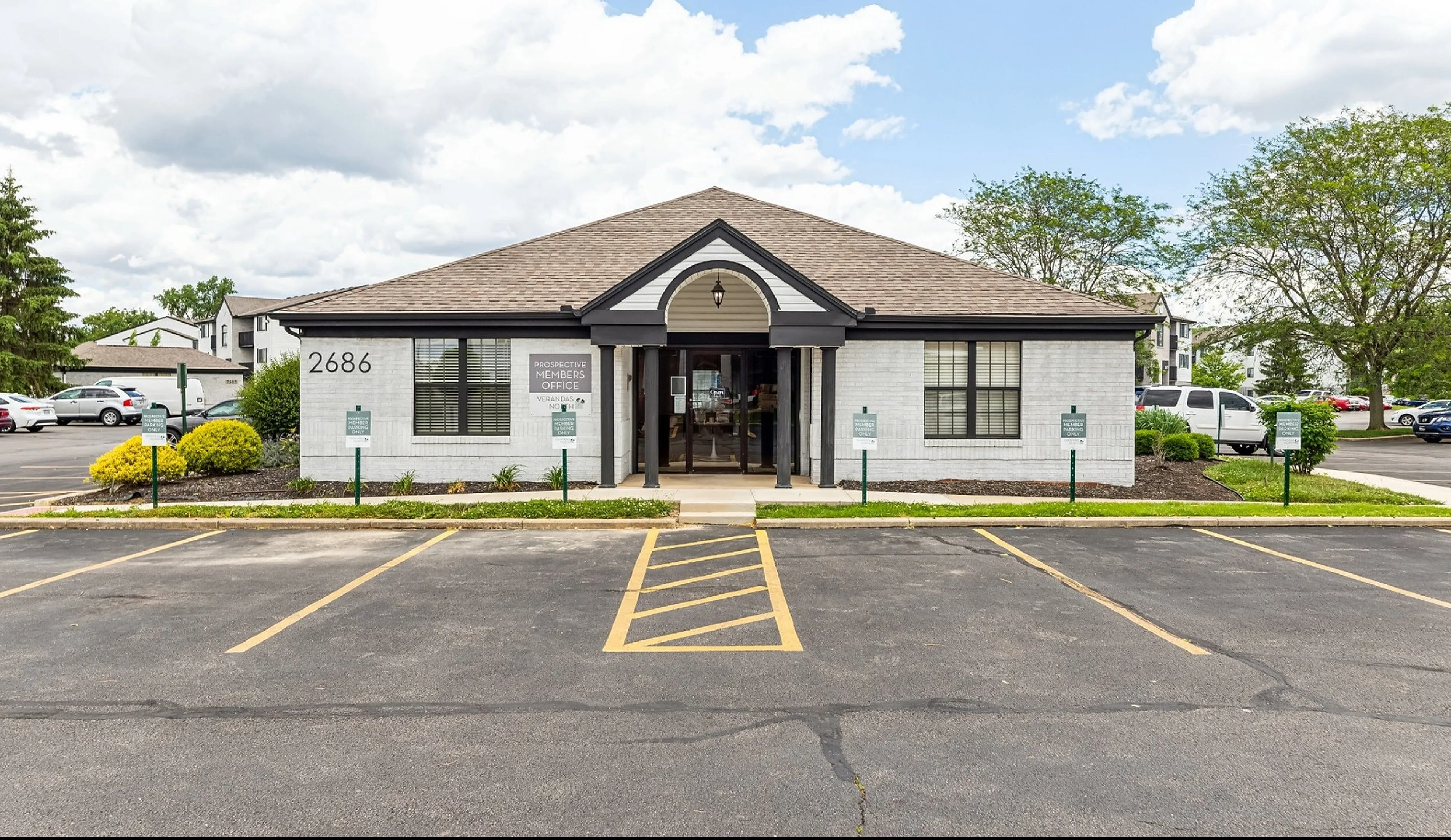 Welcoming front view of a modern leasing office with charming landscaping, ample parking, and inviting entrance.